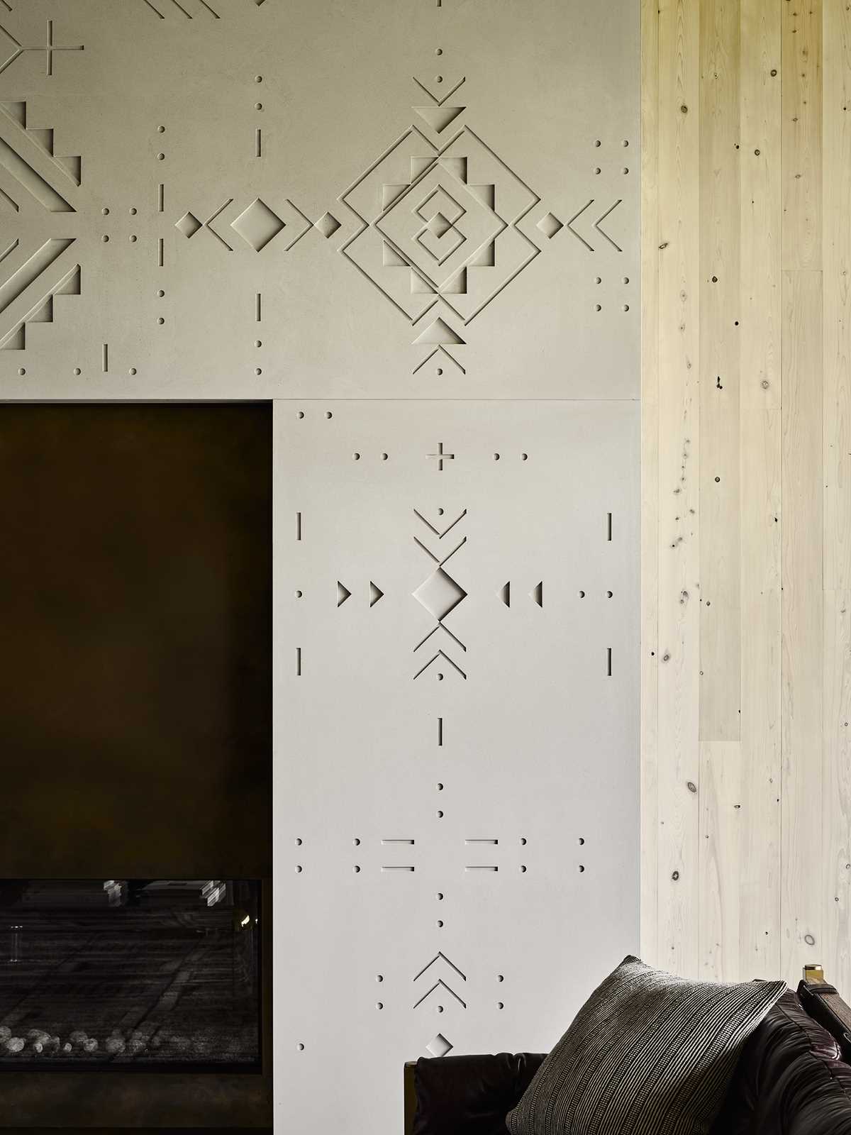 In the living room, custom-designed, tattoo-inspired bas relief concrete surrounds the fireplace.