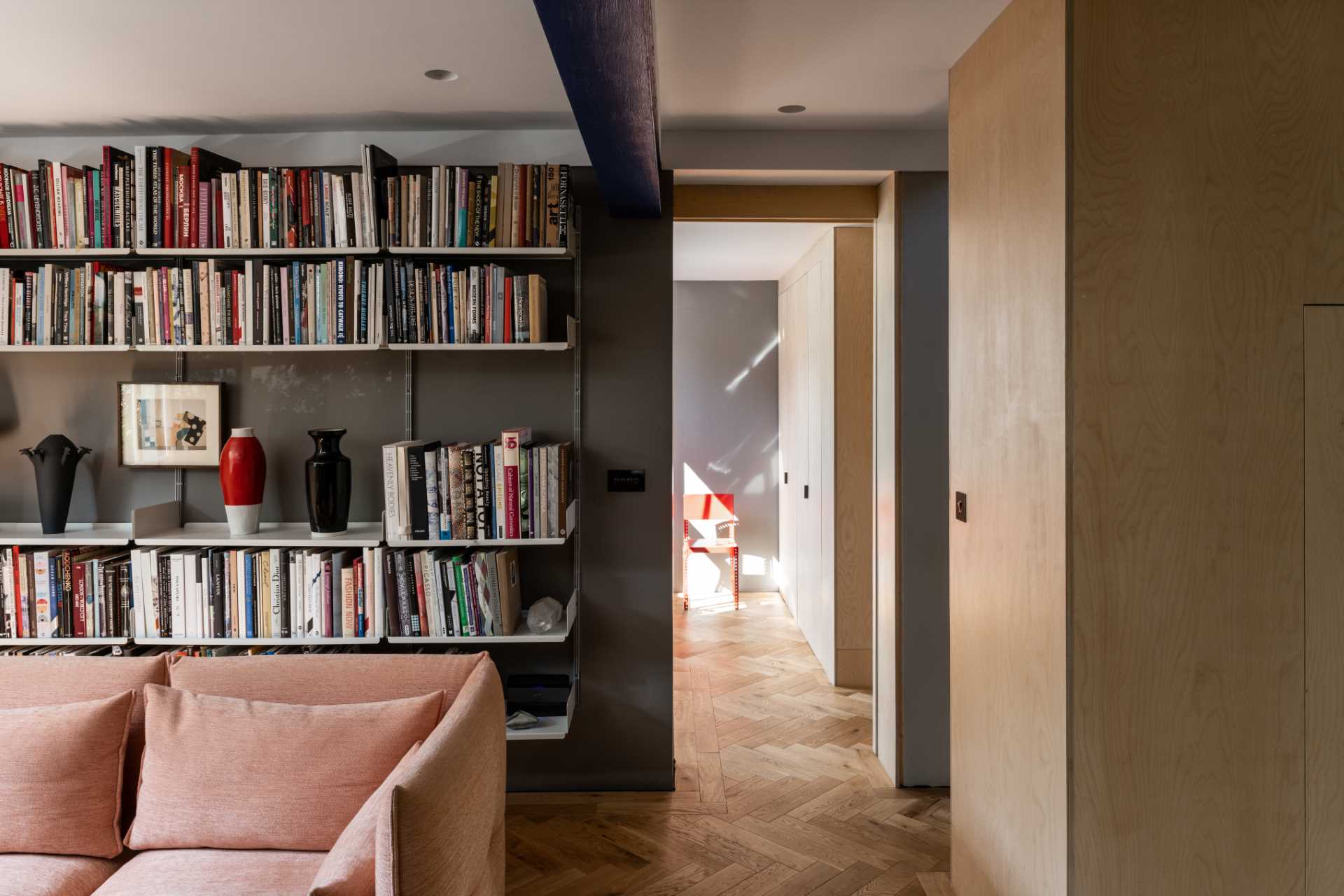 This living room, with views of the street, has wall-mounted bookshelves and dark walls.