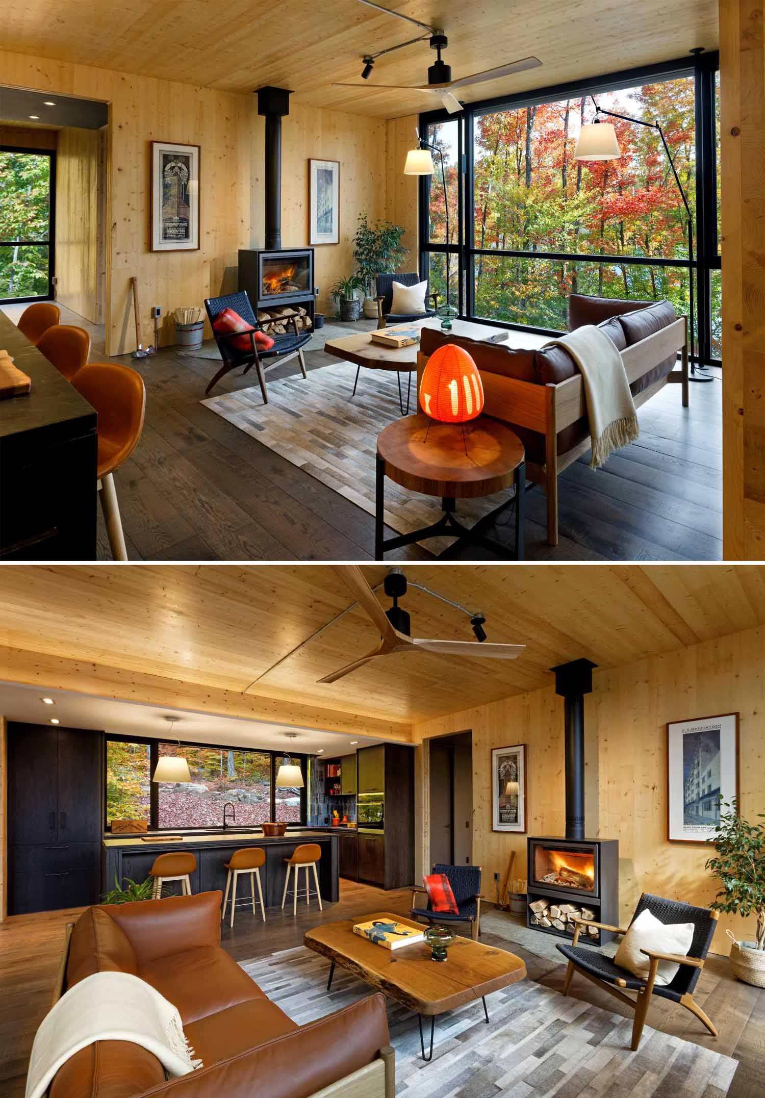 In the living room, wood walls are paired with large black-framed windows that perfectly showcase the views, and the kitchen, with its dark cabinets, offers a contrasting element to the wood walls and ceiling.