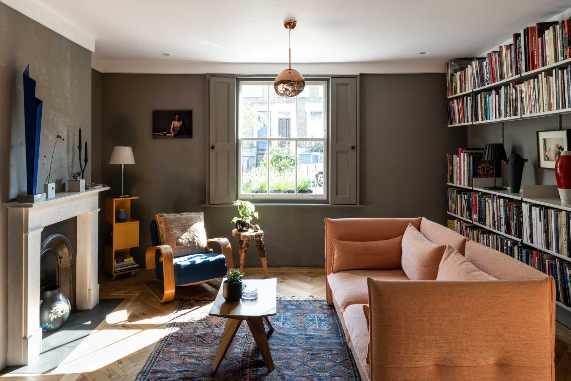 This living room, with views of the street, has wall-mounted bookshelves and dark walls.
