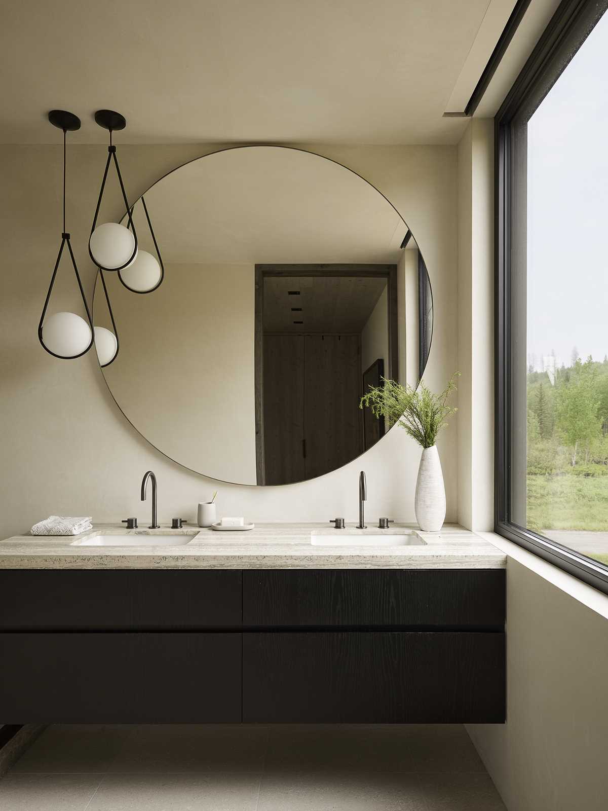 A modern bathroom with a large round mirror.