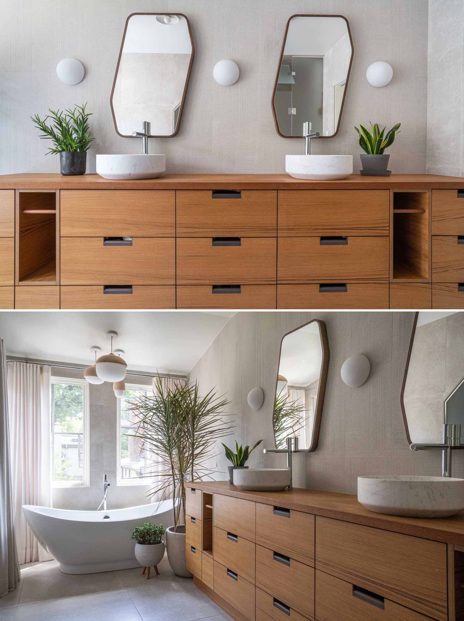 In this modern bathroom, a large wood vanity provides plenty of storage, while the round sinks complement the white wall lights, and the mirrors add a touch of fun.