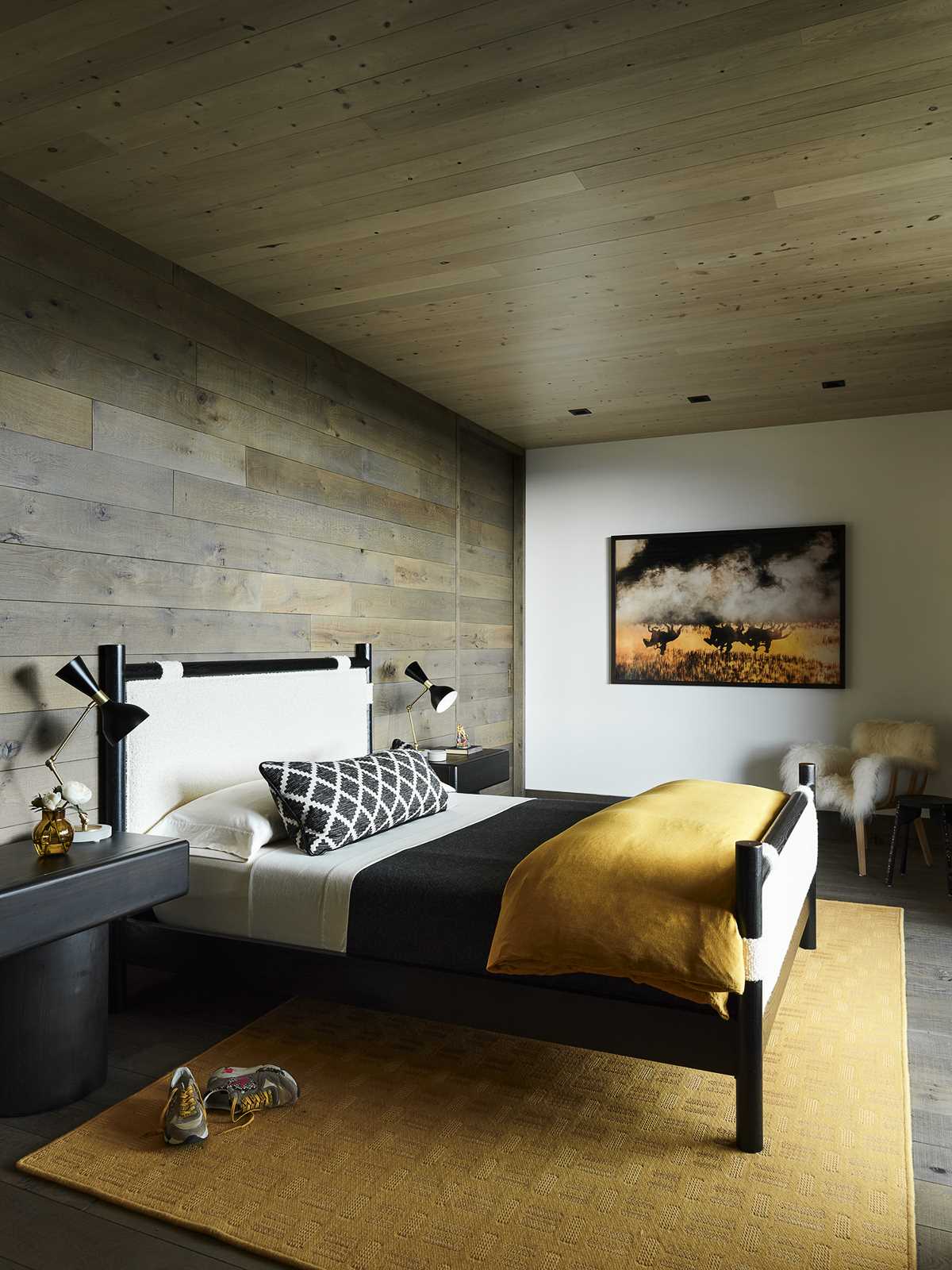 A modern bedroom with wood accent wall and black furniture.