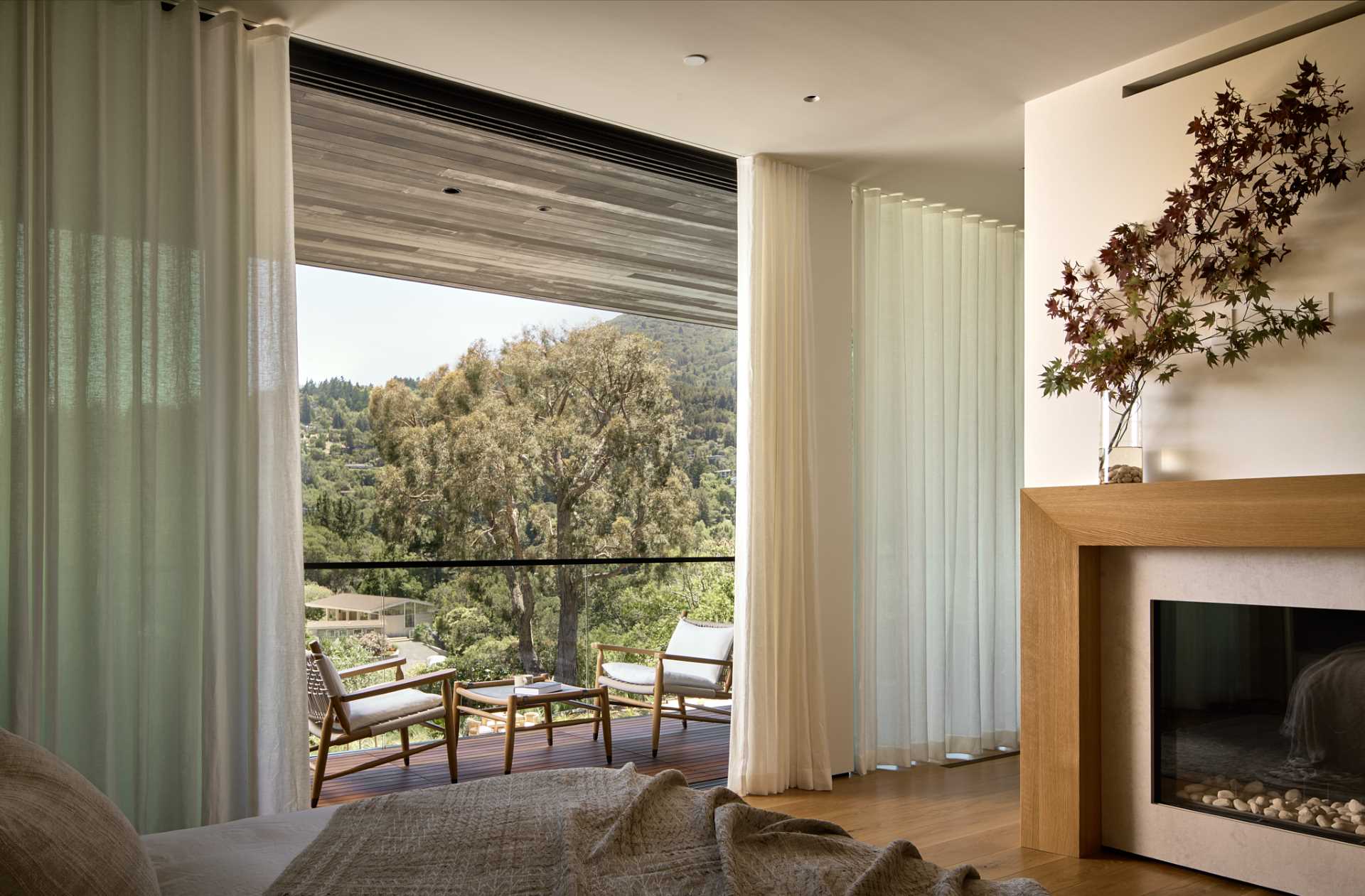 In this bedroom, floor-to-ceiling curtains open to reveal a private balcony, while a fireplace adds a sense of warmth to the room.