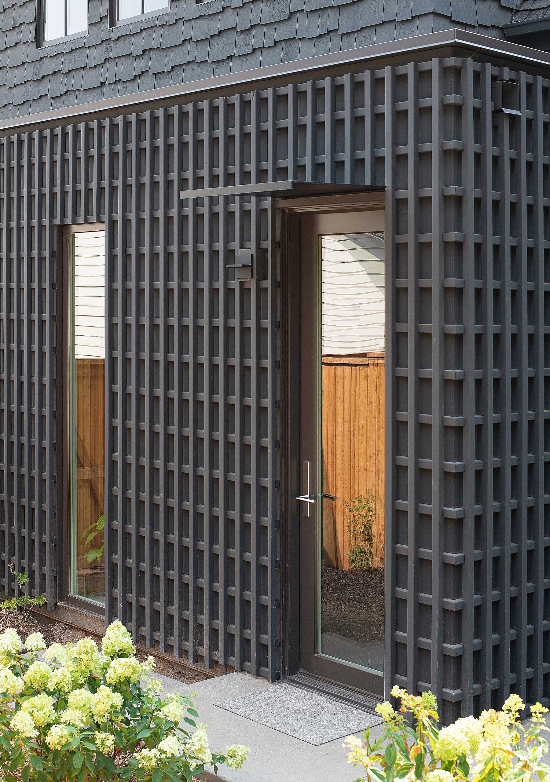 A modern home features a black lattice screen on its exterior.