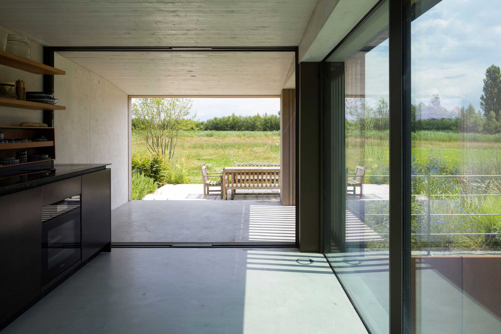 A modern house with a kitchen that opens to an oudoor dining area.