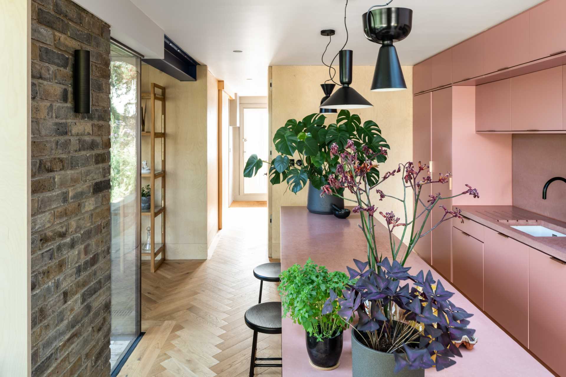 A brick home extension with a blush pink kitchen and window seats.