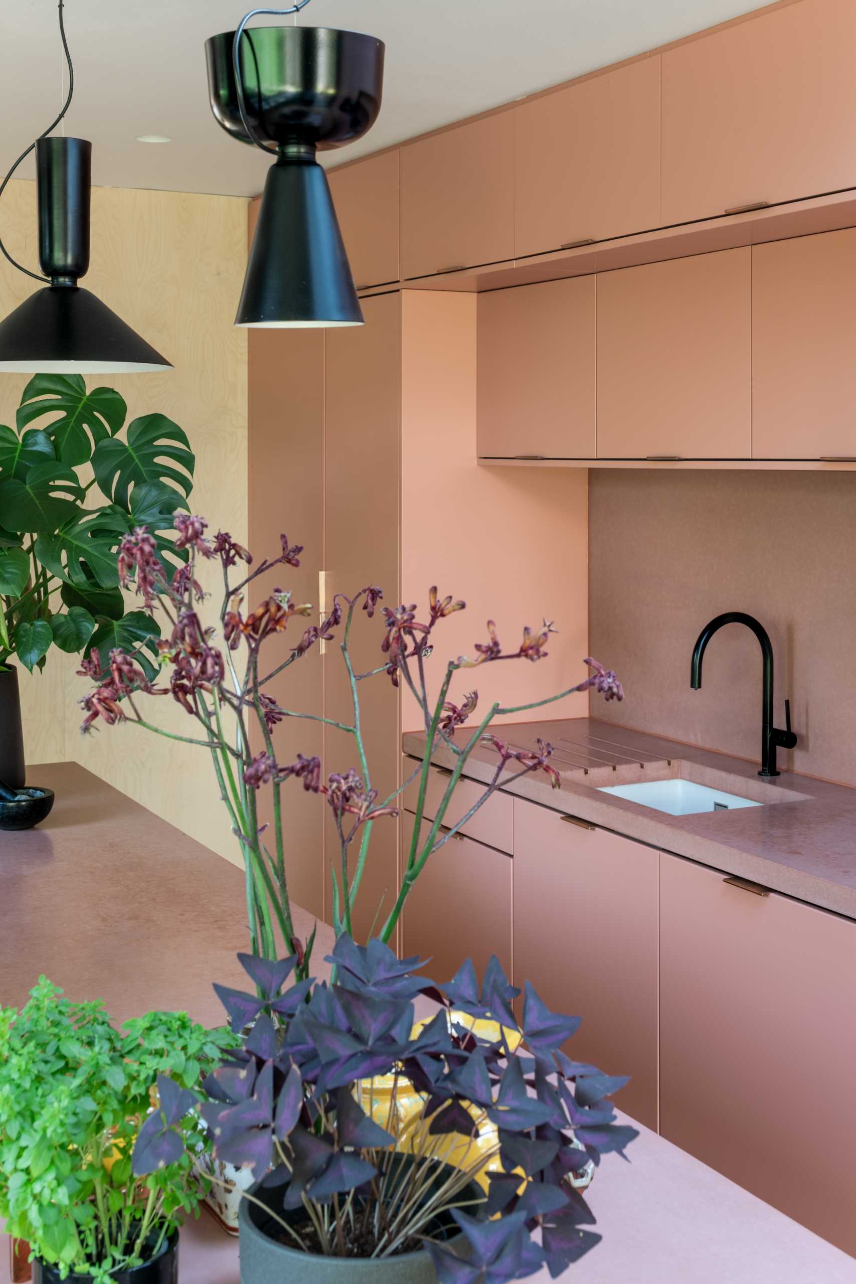 A brick home extension with a blush pink kitchen and window seats.