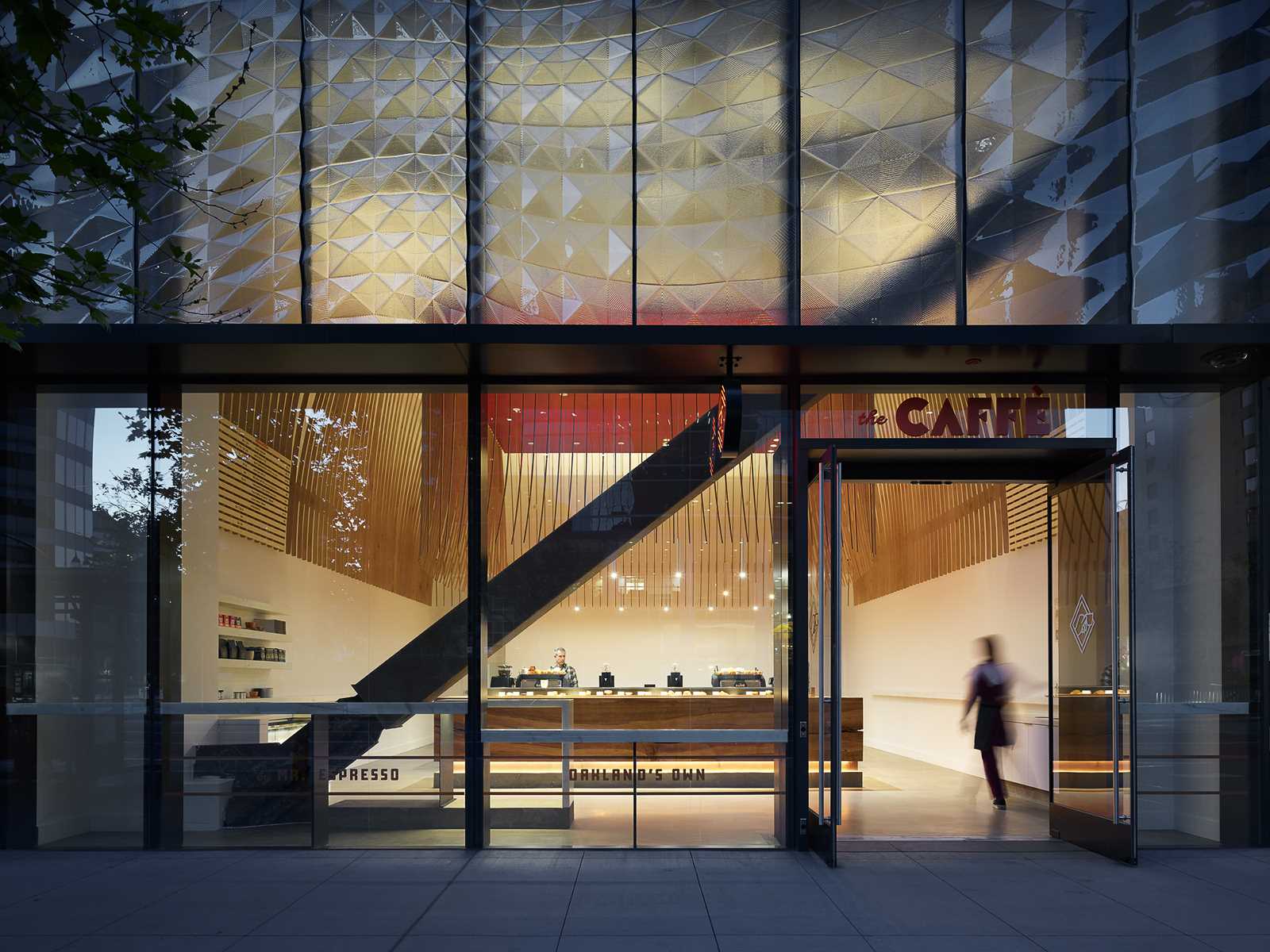 A modern coffee bar with a large wood bar and a sculptural element made from 272 wood slats.