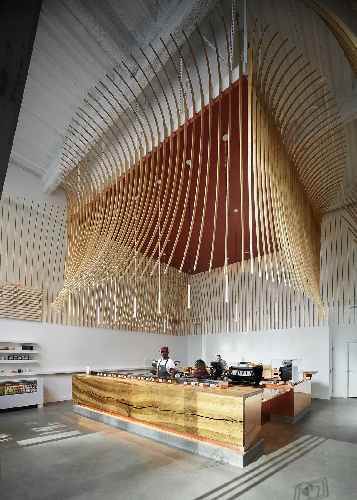 A modern coffee bar with a large wood bar and a sculptural element made from 272 wood slats.