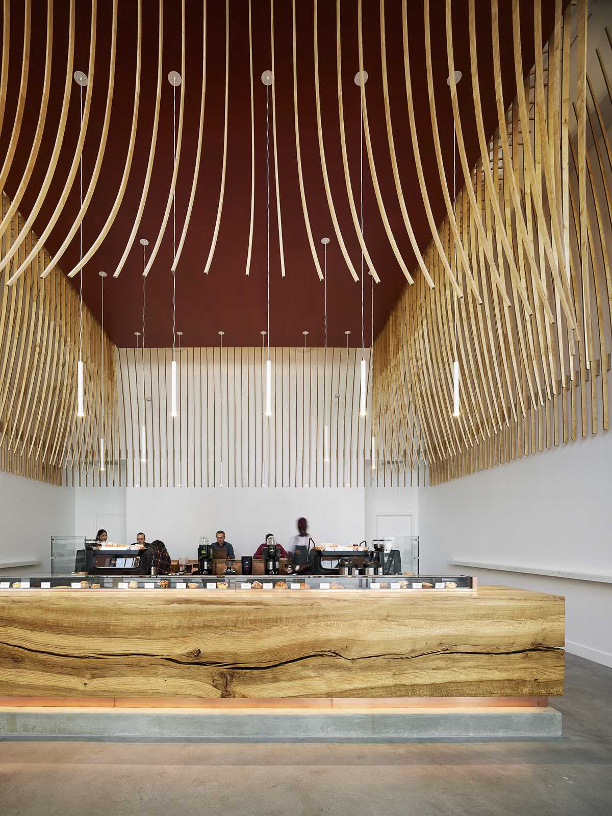 A modern coffee bar with a large wood bar and a sculptural element made from 272 wood slats.