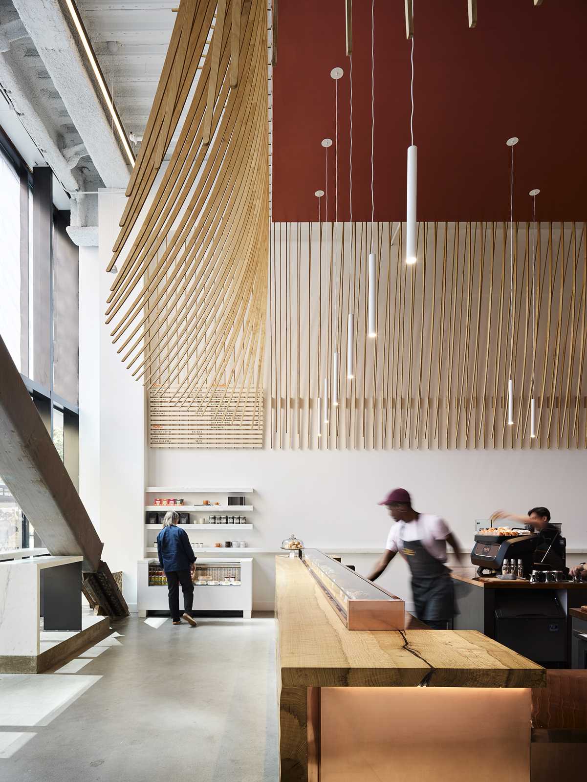 A modern coffee bar with a large wood bar and a sculptural element made from 272 wood slats.