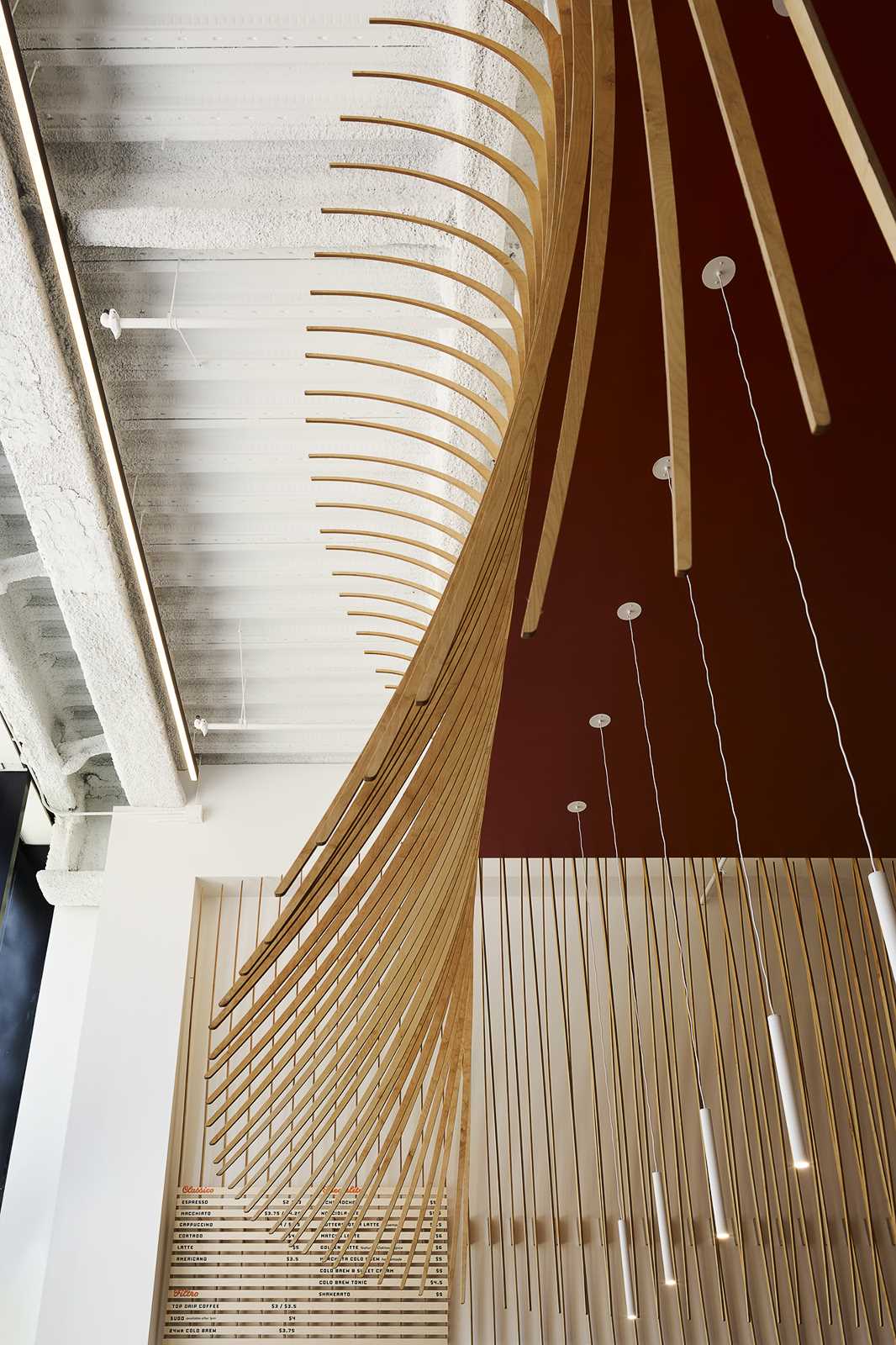 A modern coffee bar with a large wood bar and a sculptural element made from 272 wood slats.