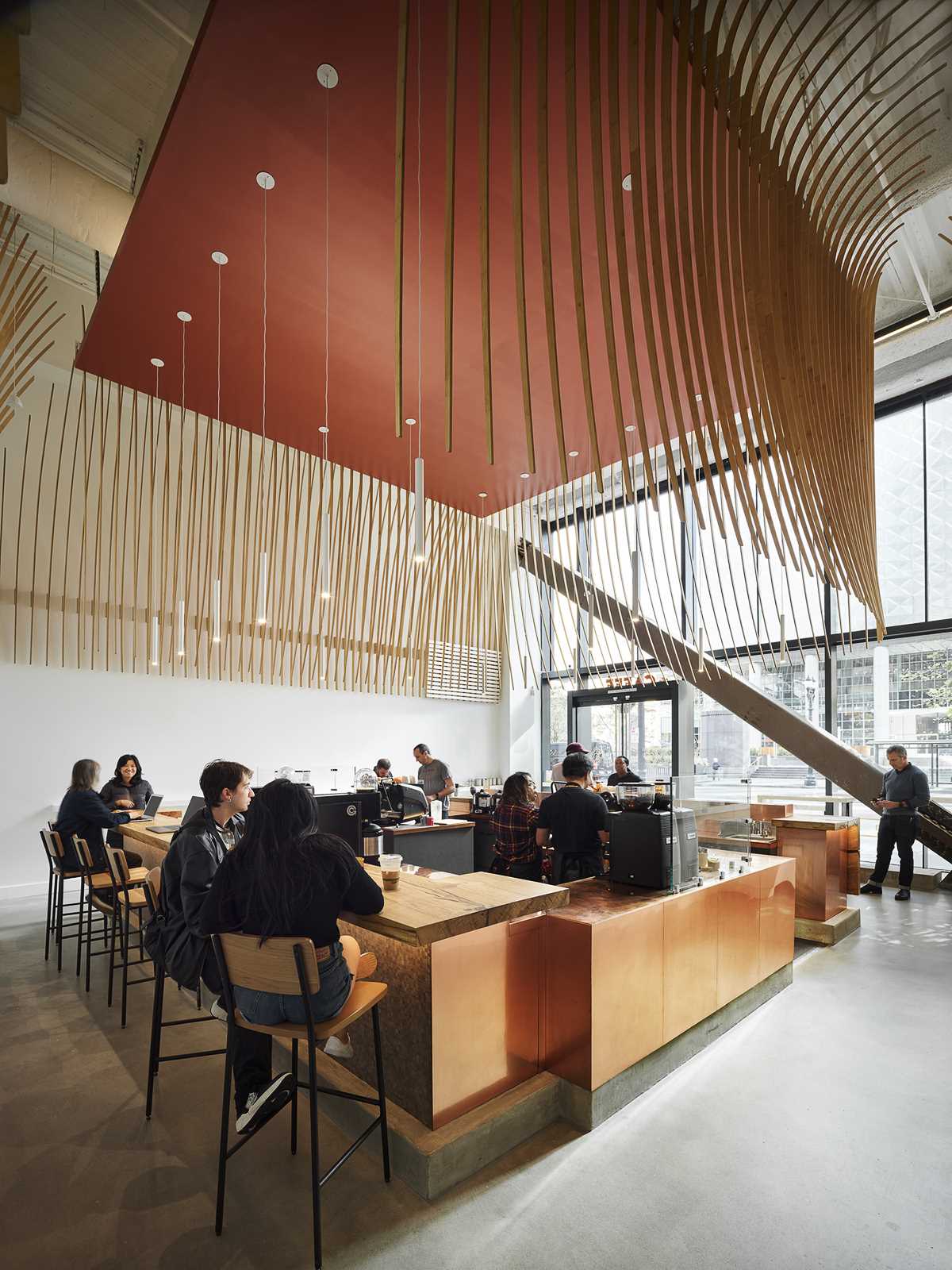 A modern coffee bar with a large wood bar and a sculptural element made from 272 wood slats.