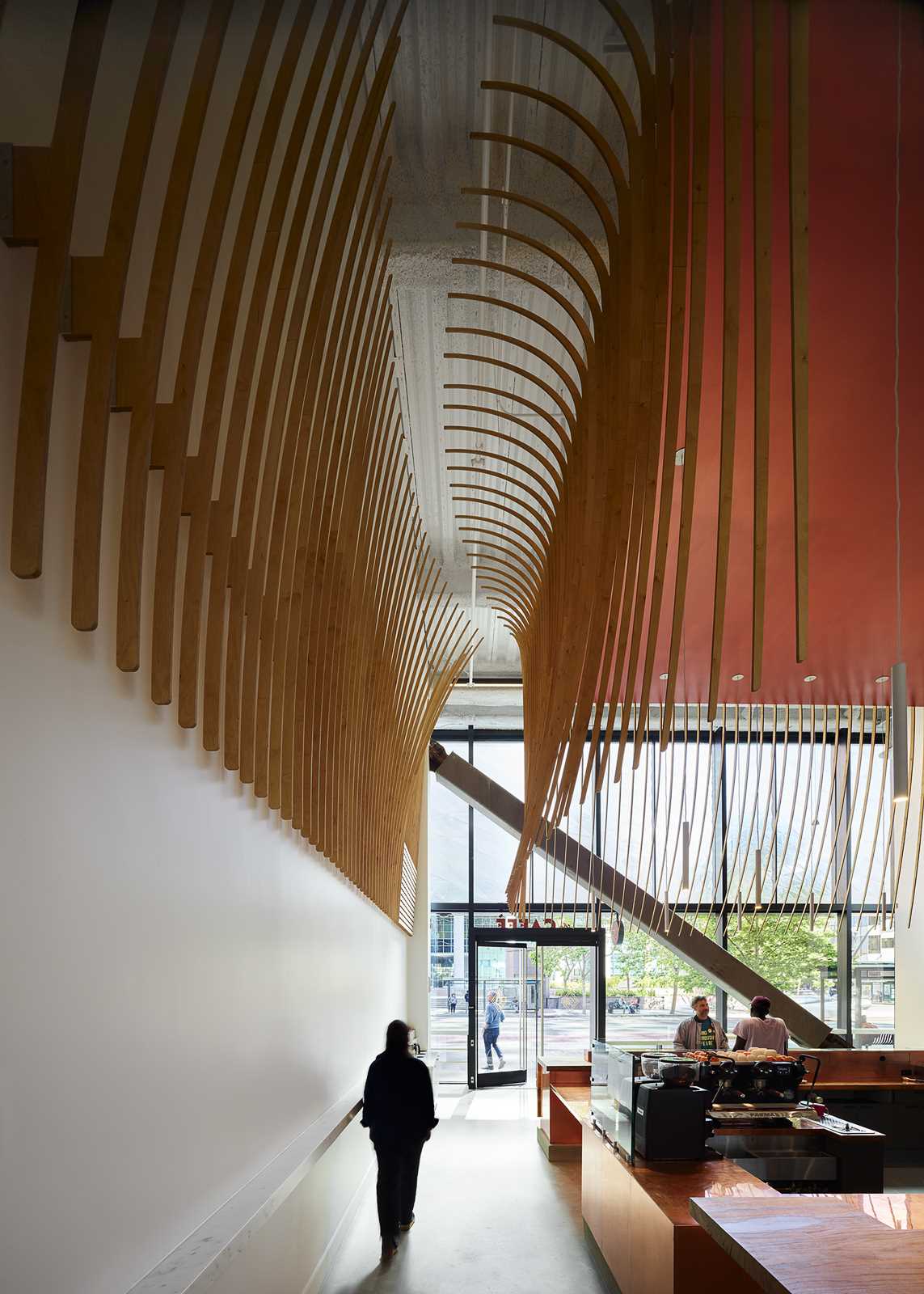 A modern coffee bar with a large wood bar and a sculptural element made from 272 wood slats.