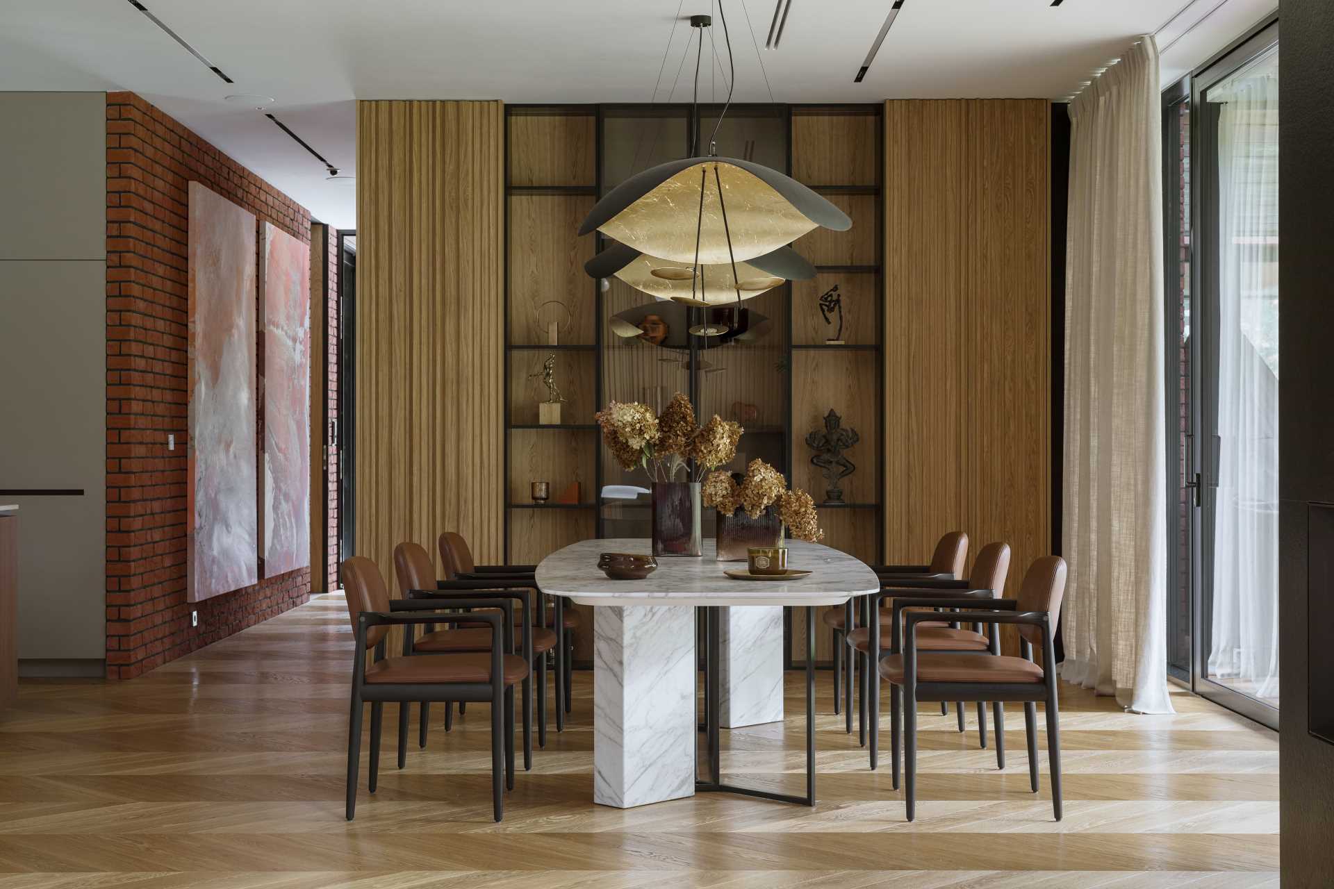 Aged brick, black steel, and corten-color elements appear inside this modern house, like in the dining room.