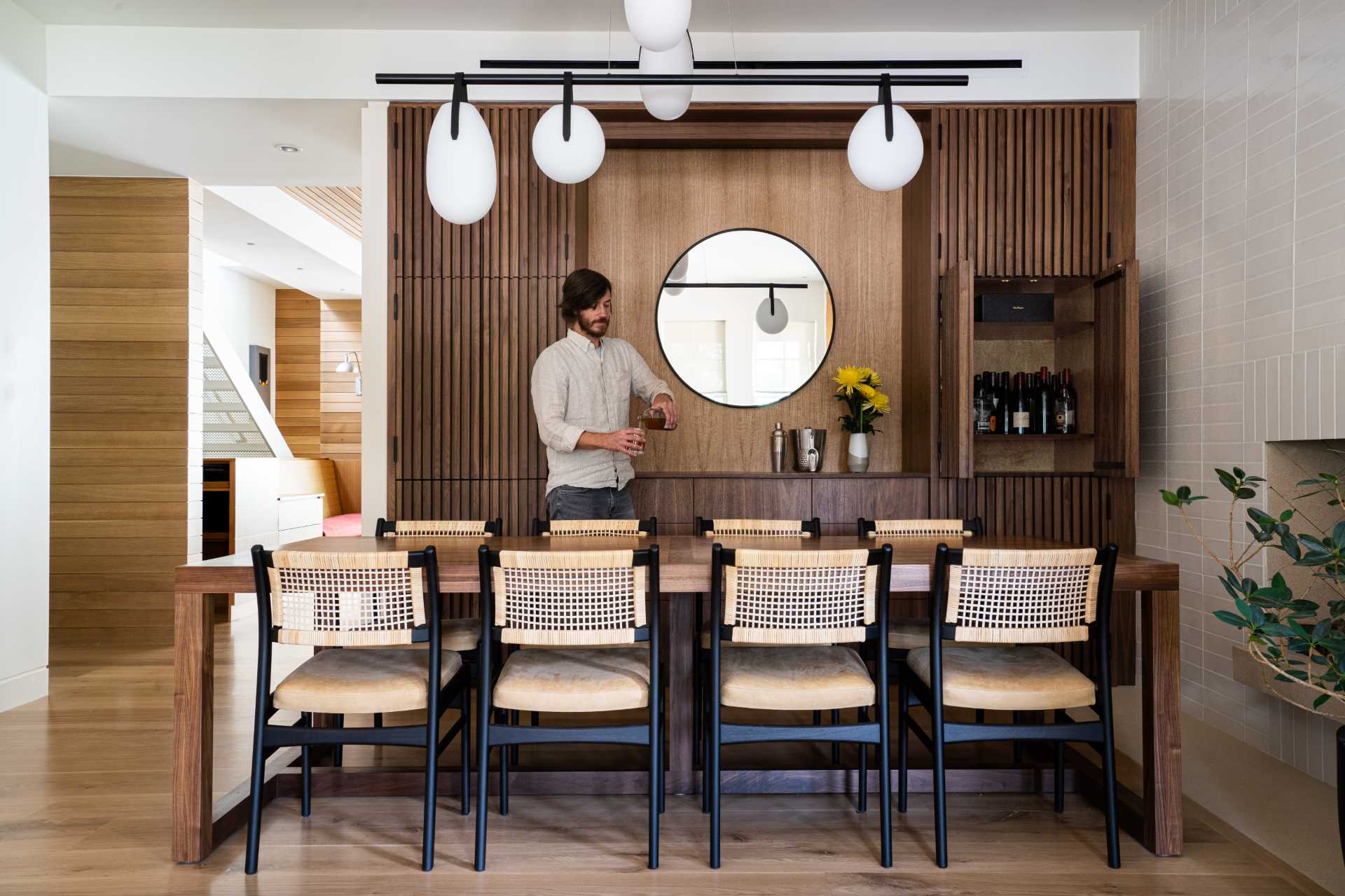 In this dining room, dark cabinetry provides plenty of storage while the mirror helps to reflect light in the space.