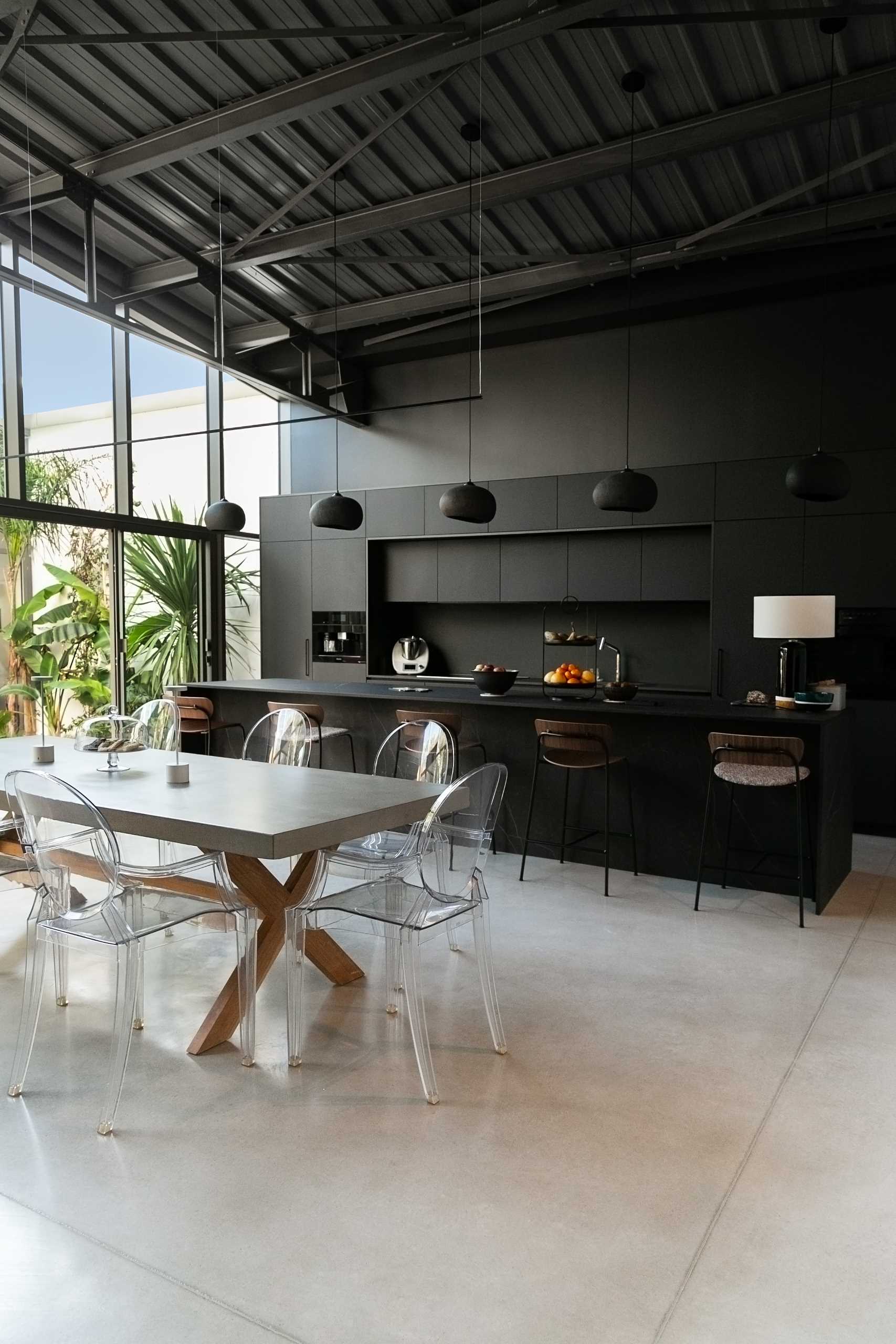 A warehouse conversion with a minimalist black kitchen and open plan dining area.
