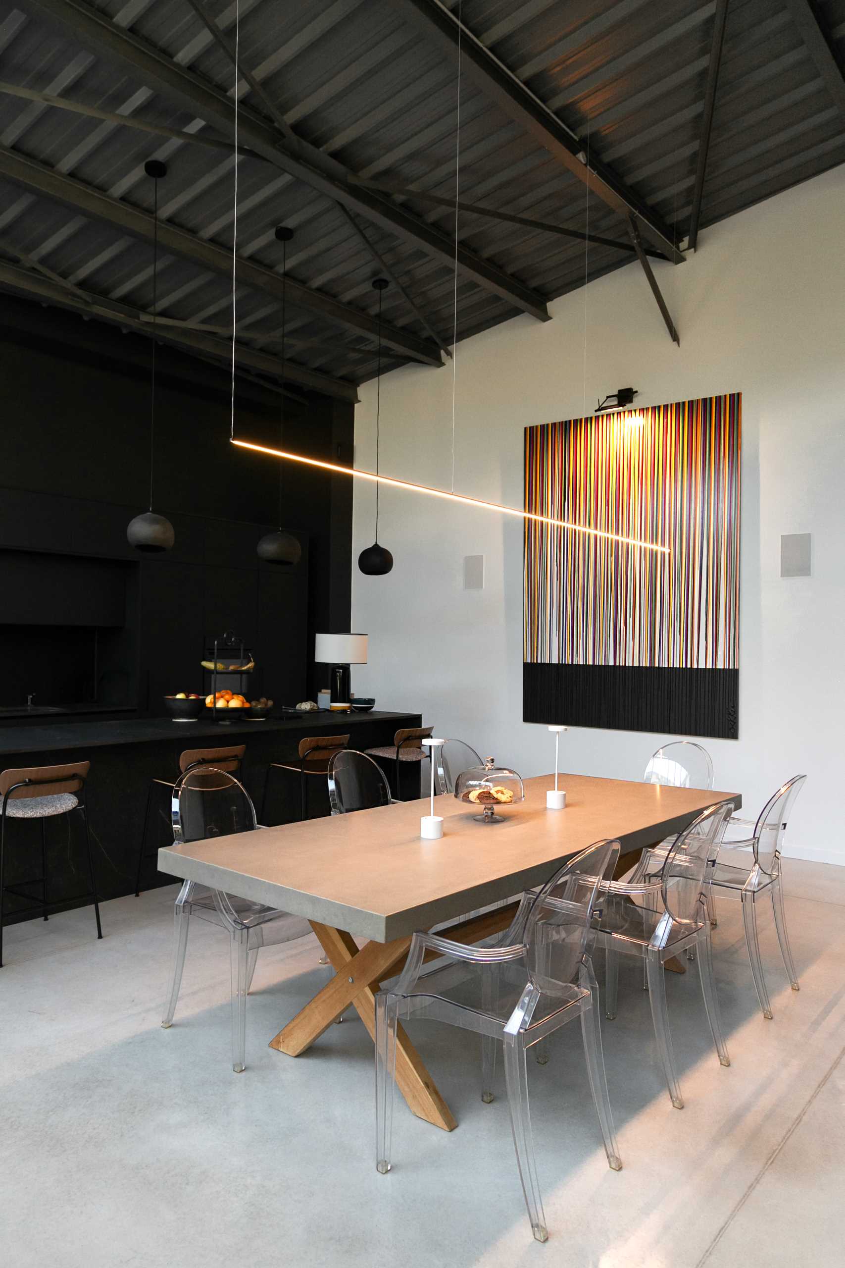 A warehouse conversion with a minimalist black kitchen and open plan dining area.