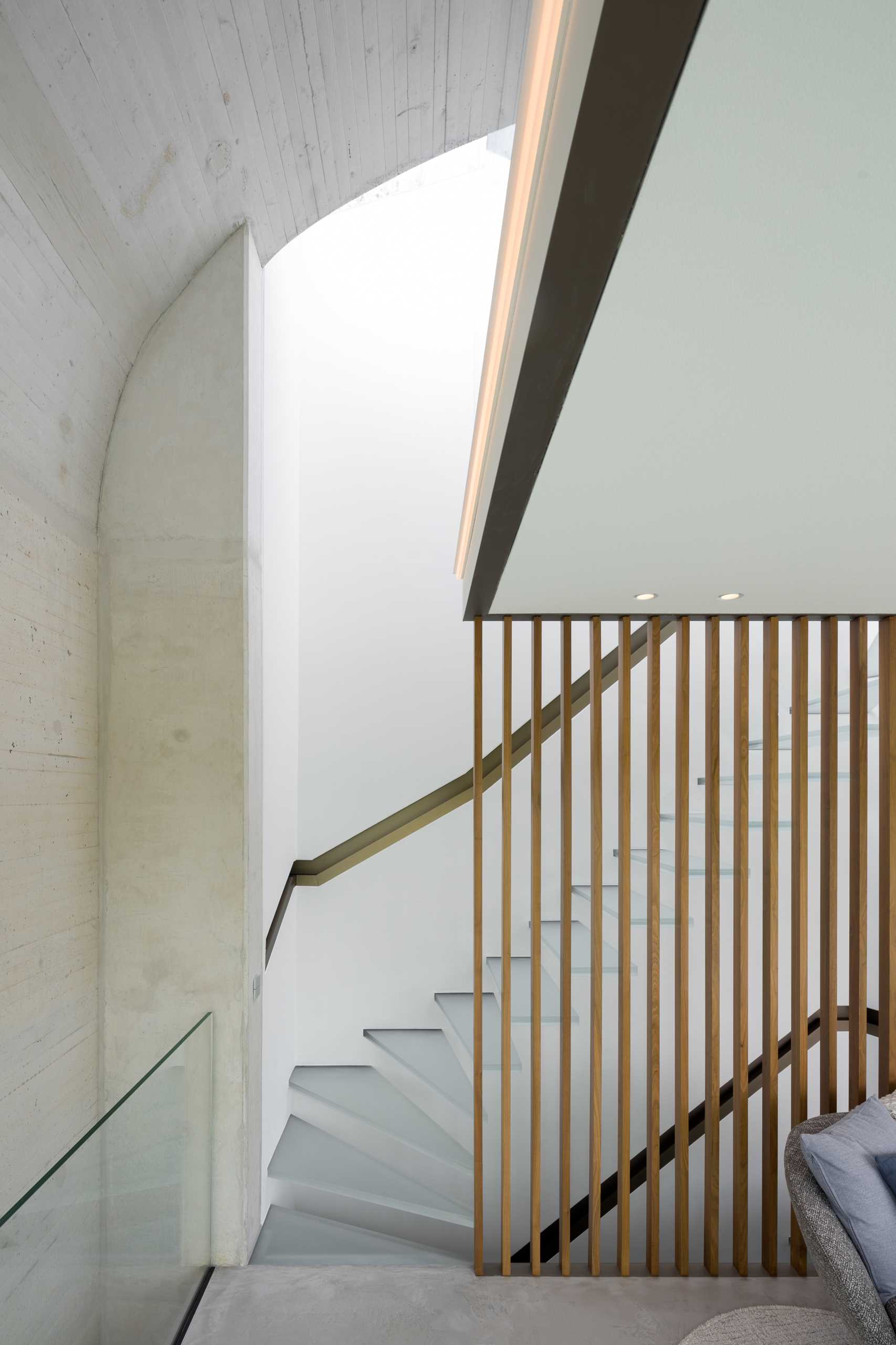 A glass staircase connects to the lower levels of the home.