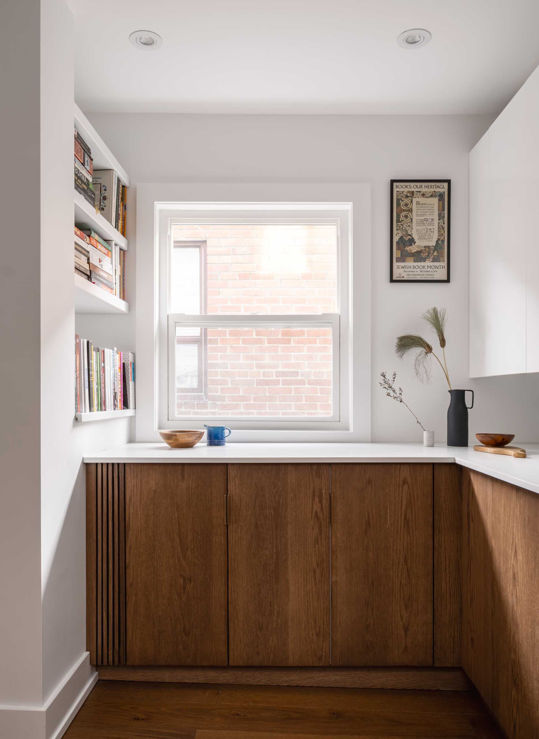 A modern kitchen with dark wood and white cabinets, white countertops, Dutch “Delft” tile, and brass-lined arches.