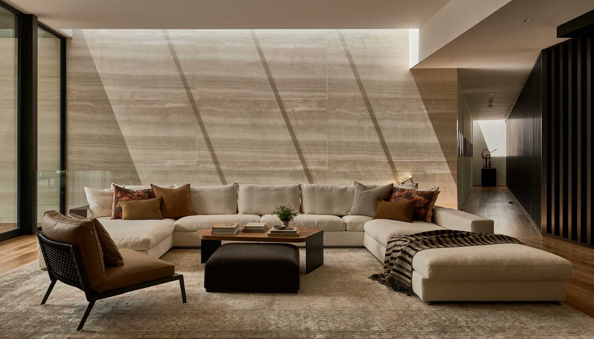 In this living room, a large couch provides ample seating, while the travertine wall adds a natural element to the ،e.