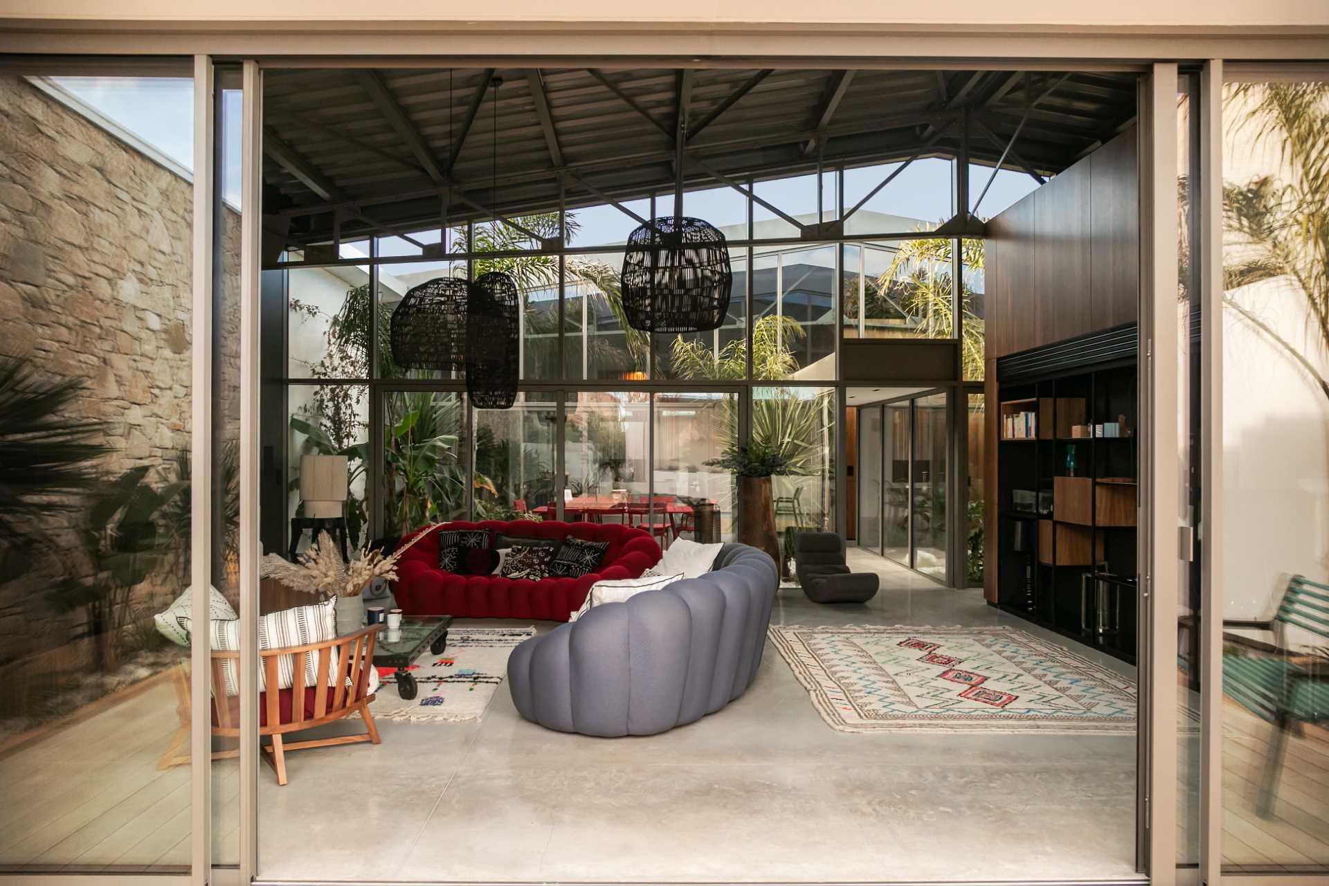 In this modern living room in a warehouse conversion, a library built-in library adds storage, while a pop of color has been added to the space in the form of a red couch, while a storage unit runs along the wall.