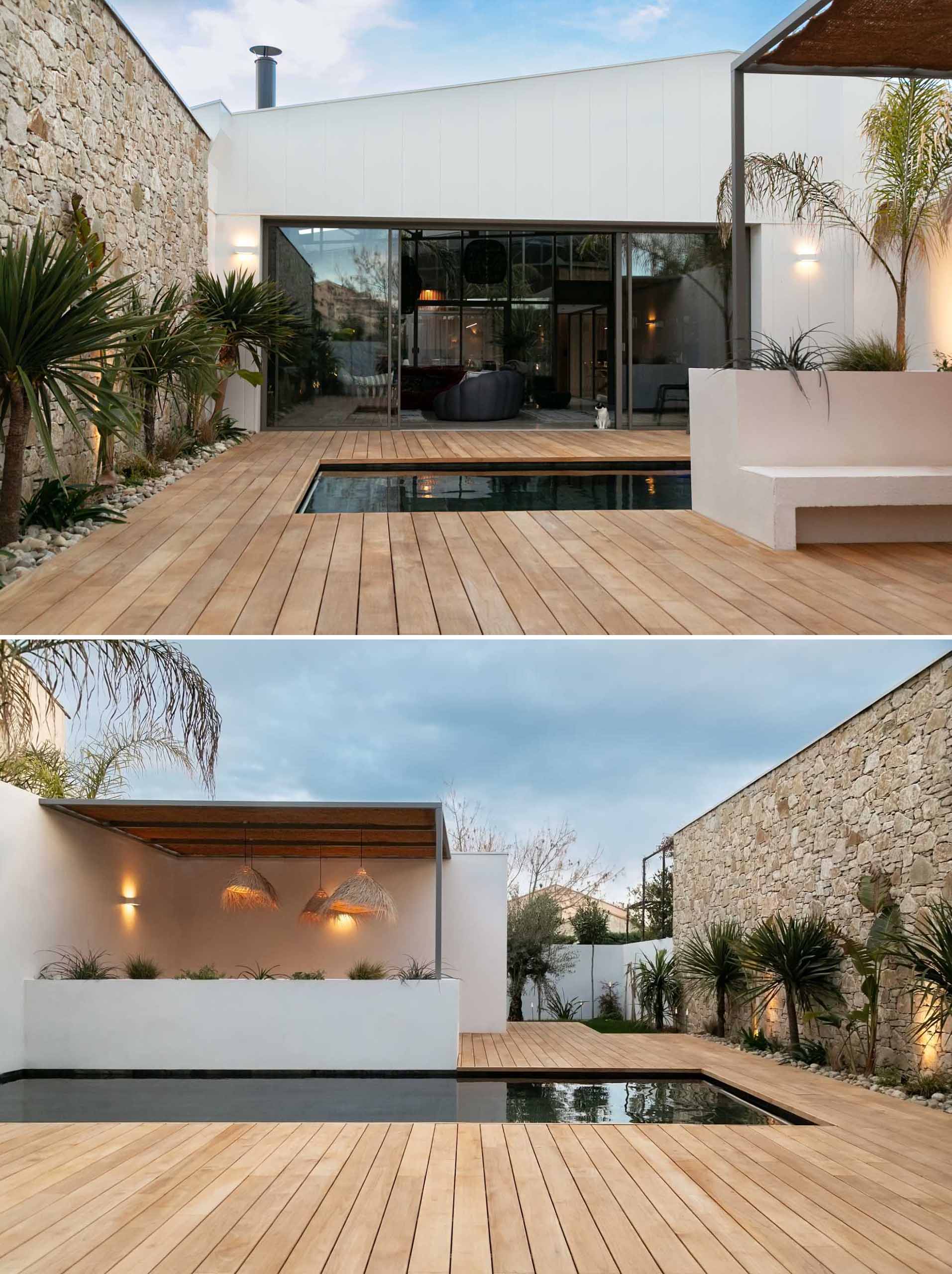 Sliding doors open the living room to the outdoor ،e that includes a wood deck surrounding a pool, and a covered seating area.