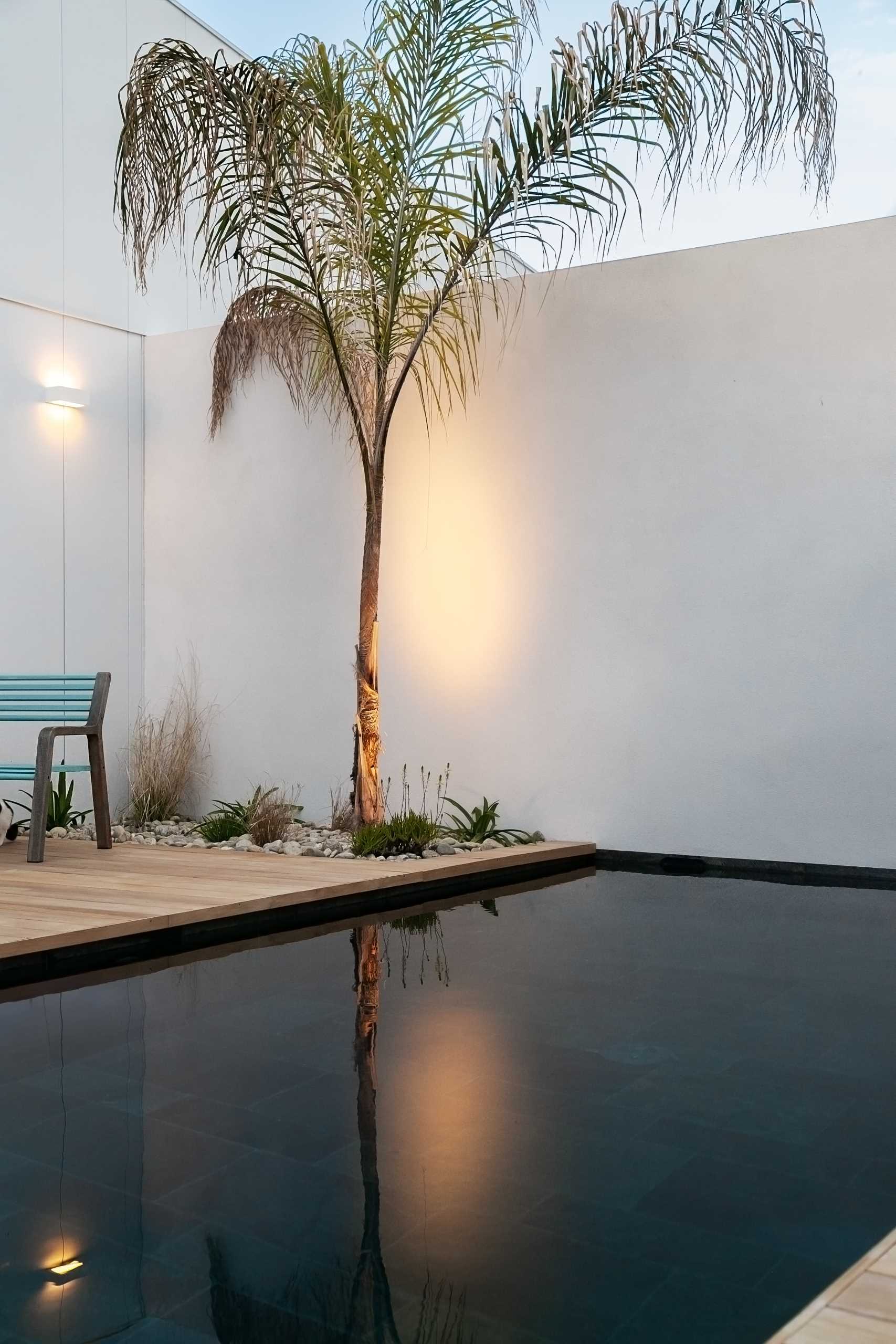 Sliding doors open the living room to the outdoor space that includes a wood deck surrounding a pool, and a covered seating area.