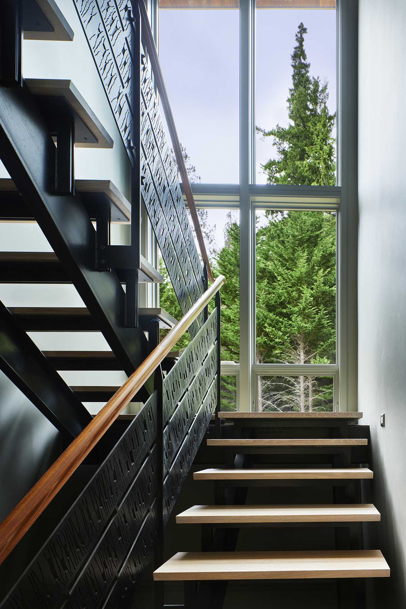 The spare steel and wood main stair is positioned to take advantage of the view through the double-height windows, which also provide natural light to the interior.