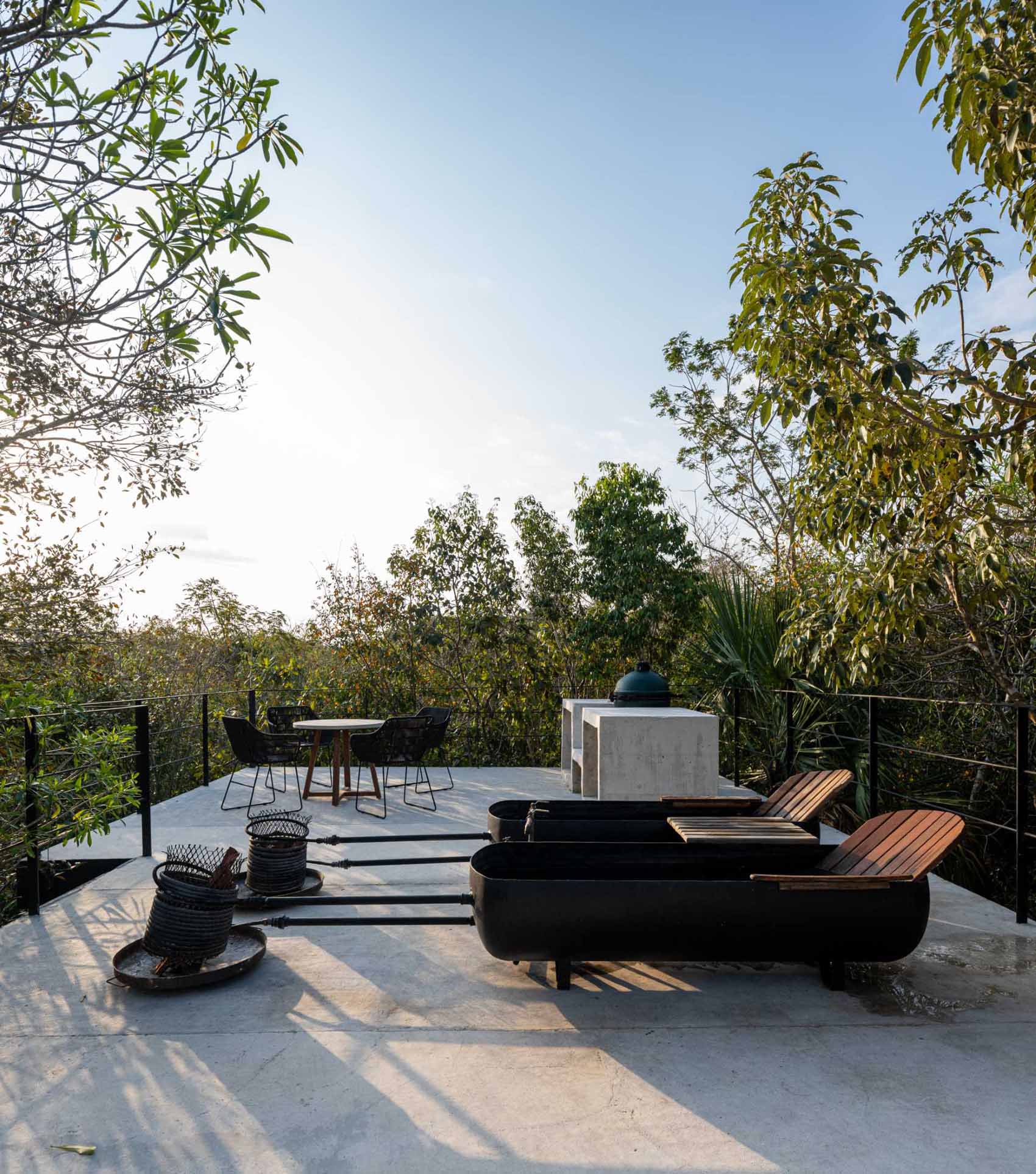 The rooftop of a tiny home features a bbq area, a dining area, and 2 wood-fired tubs.