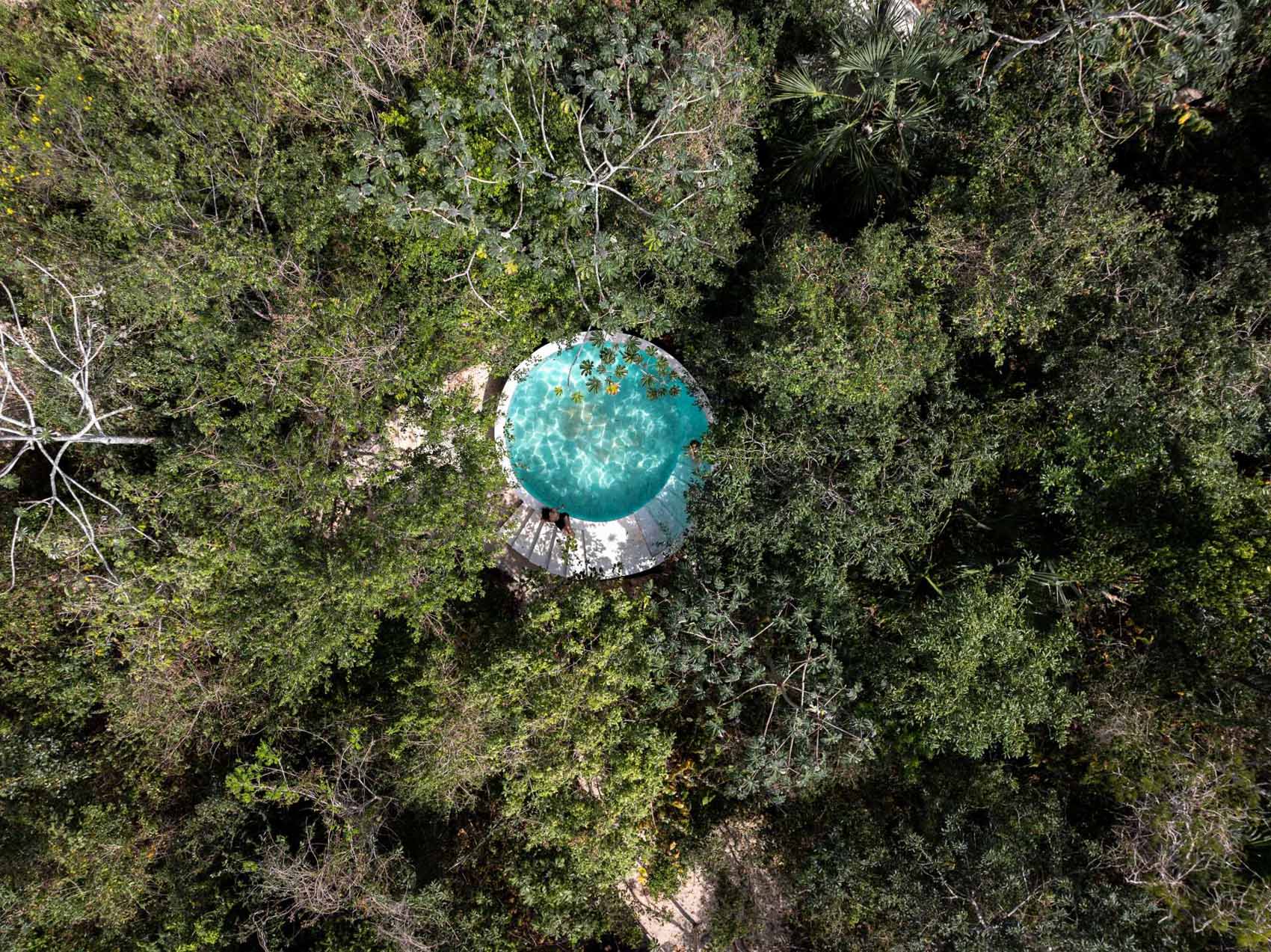 A round swimming pool that's designed as part of an off-grid collection of glass  and steel tiny homes.