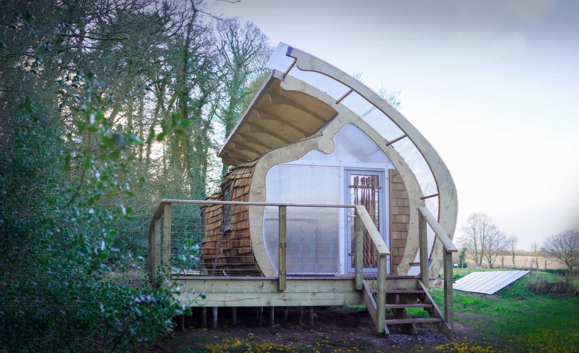 A small organically shaped cabin clad in wood shingles.