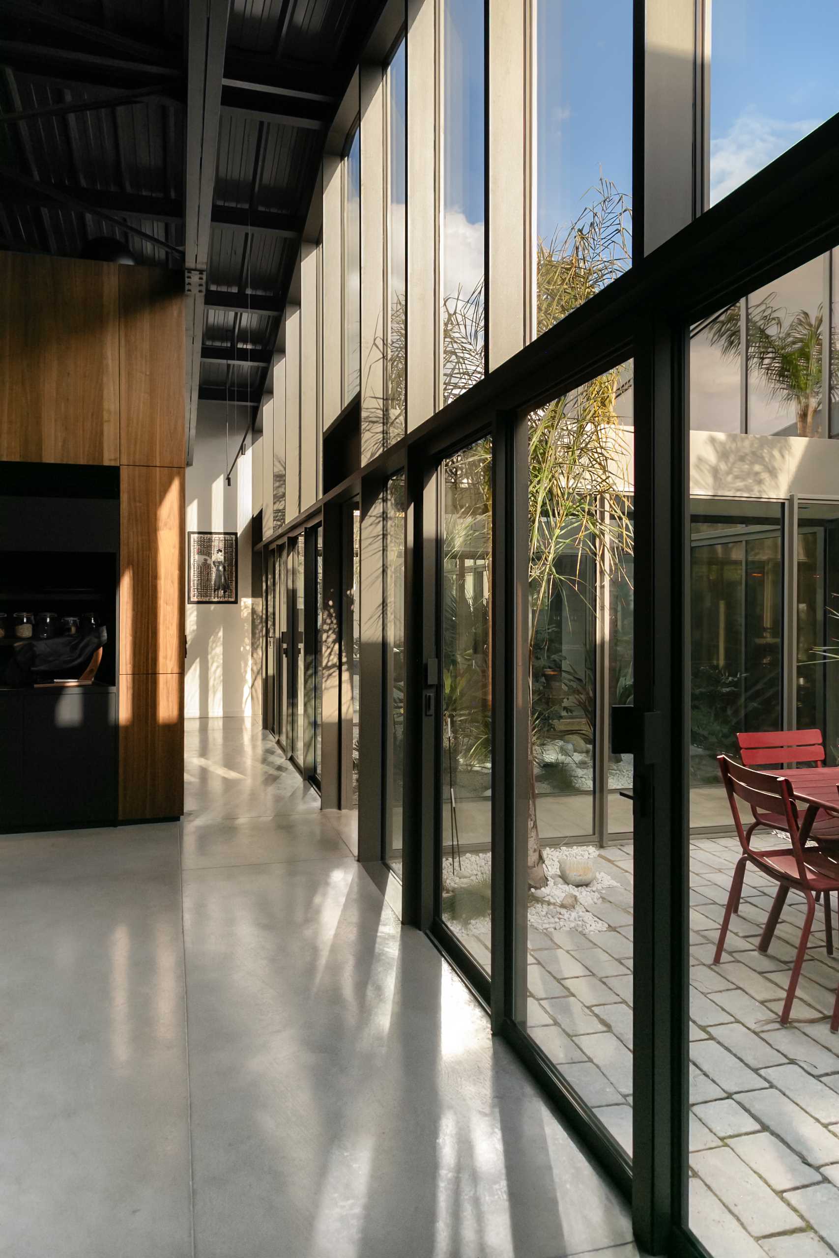 Throughout this modern warehouse conversion, walls of windows flood the interior with natural light, brightening the dark elements, while polished concrete flooring retains the industrial look.
