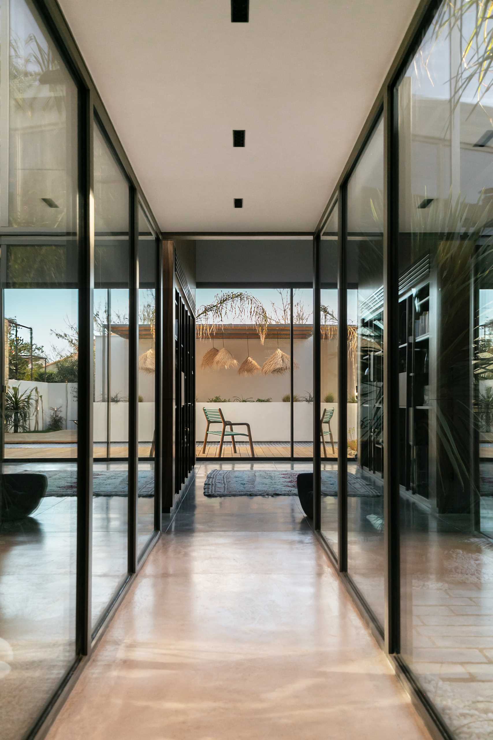 Throughout this modern warehouse conversion, walls of windows flood the interior with natural light, brightening the dark elements, while polished concrete flooring retains the industrial look.