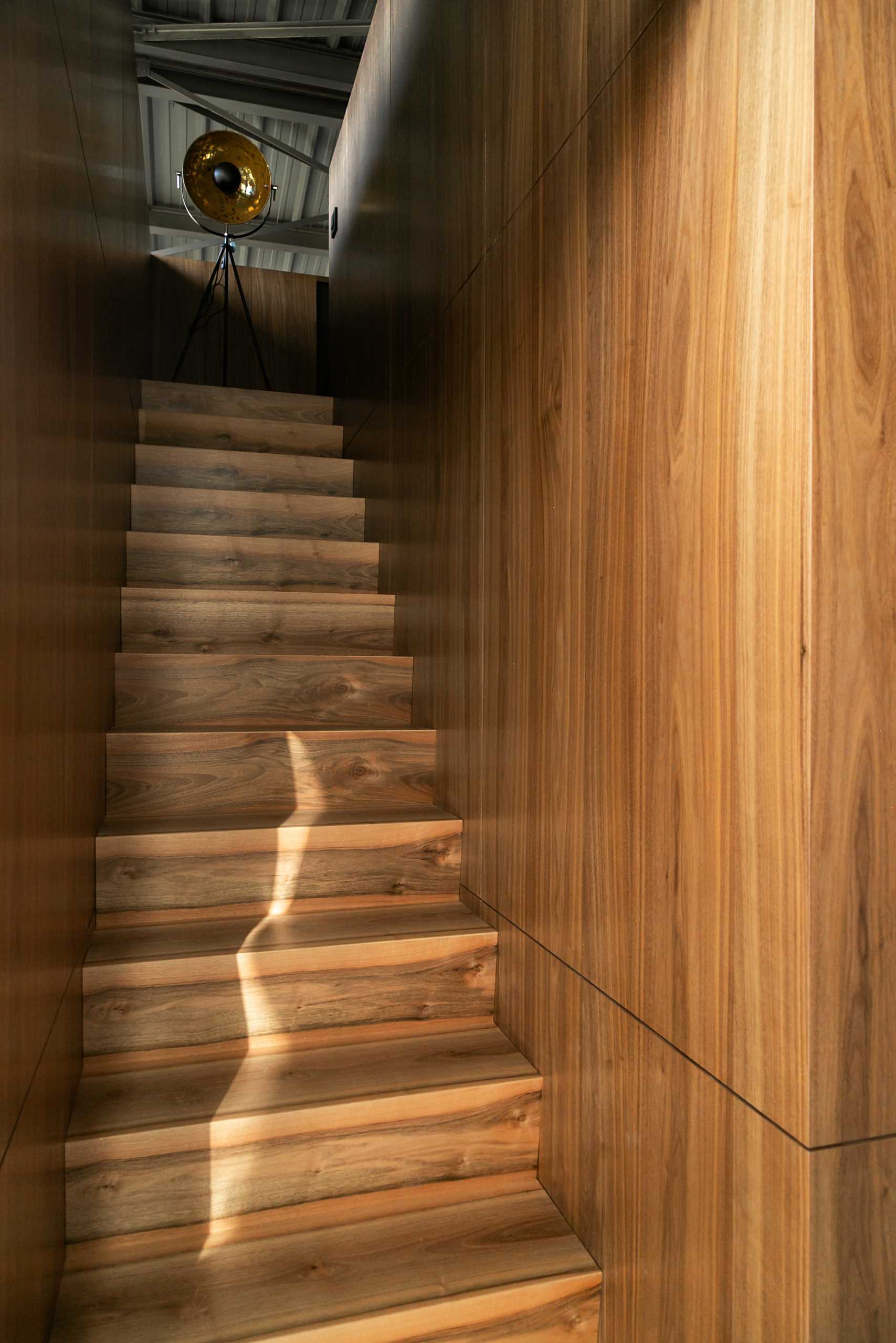 Wood stairs lead to a mezzanine on top of a wood-clad box.