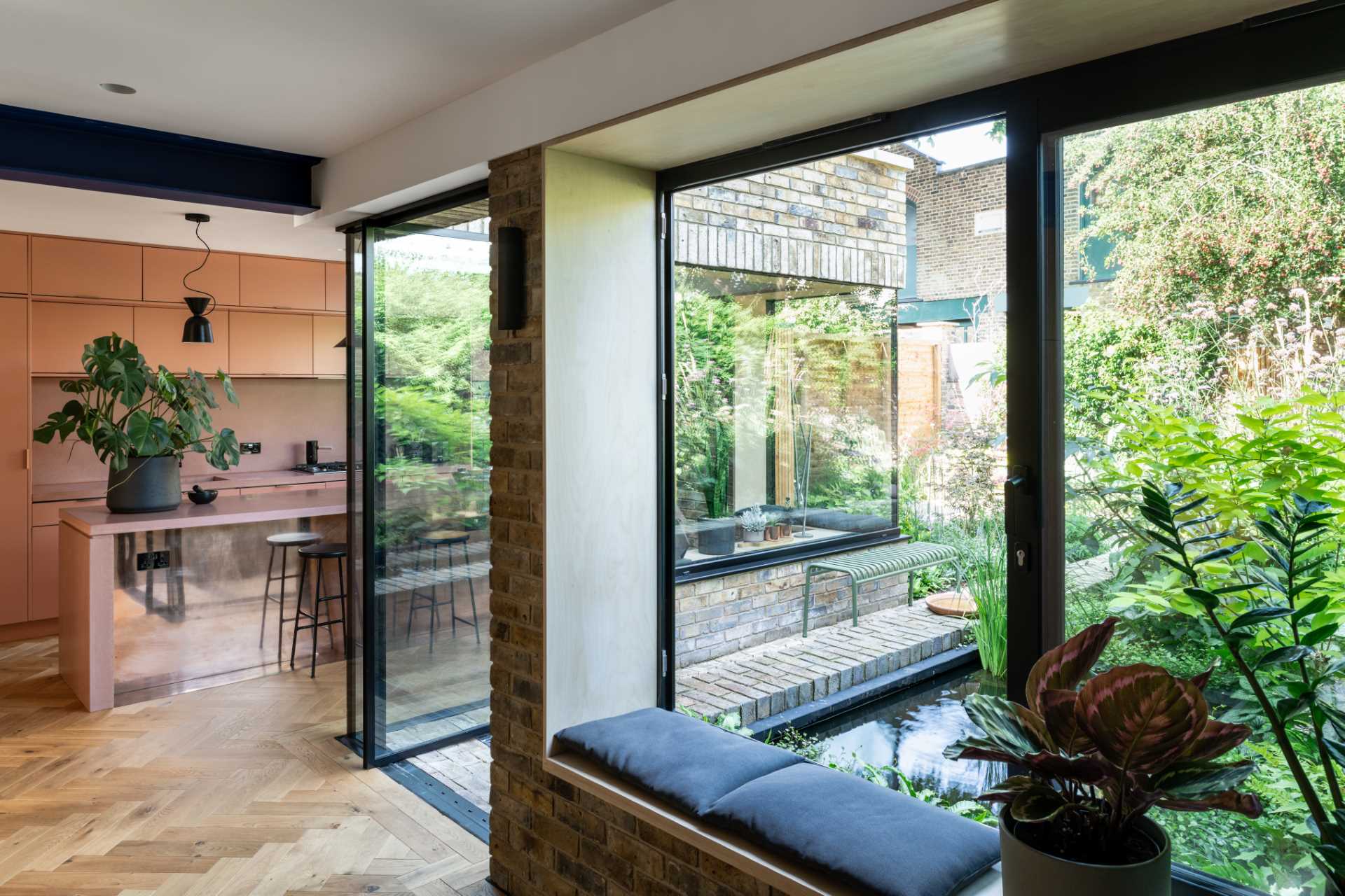 A brick home extension with a blush pink kitchen and window seats.