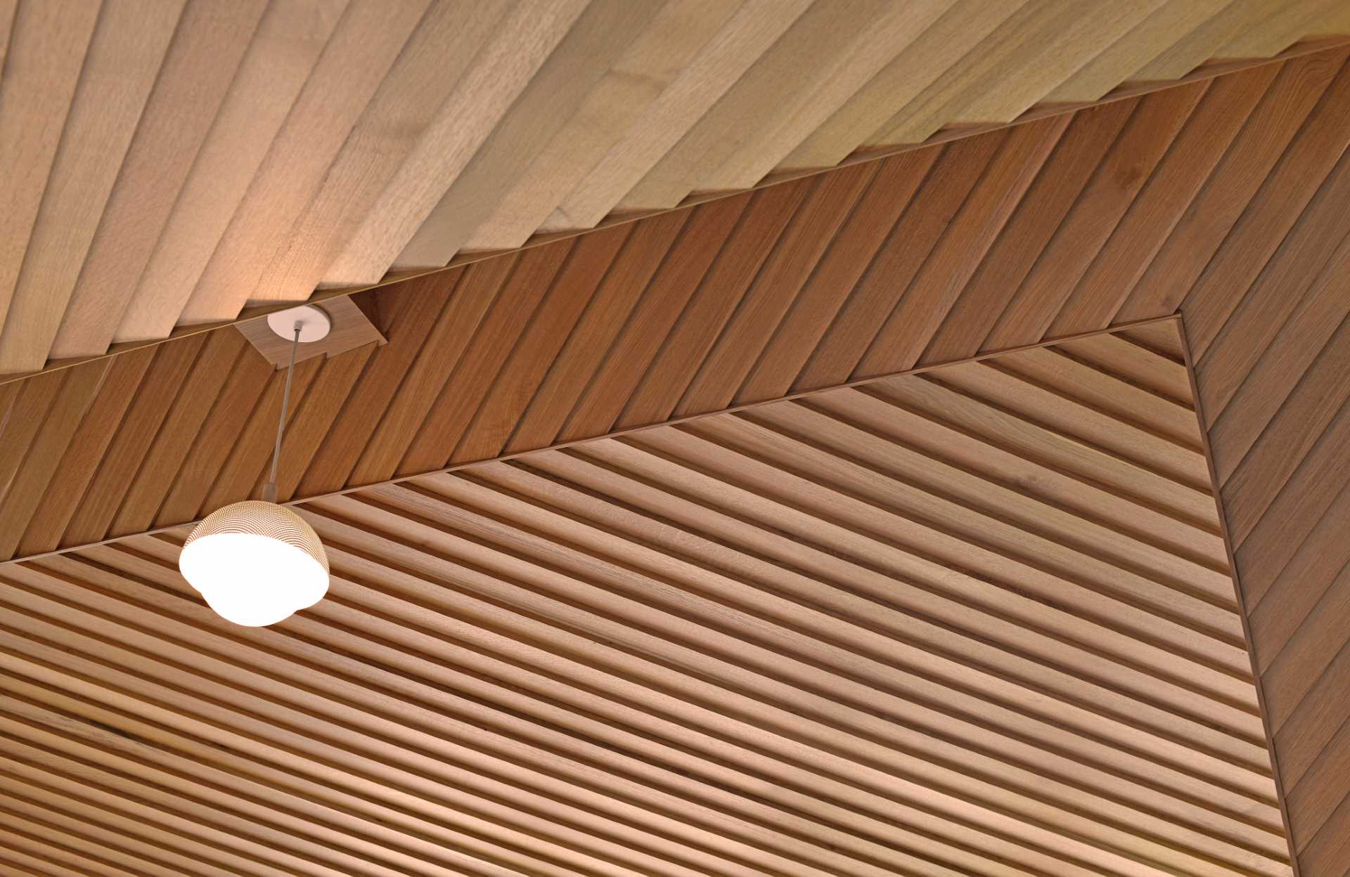 In this main bedroom, the ceiling is composed of lap siding installed at an angle, aligned perfectly at the ridge, while built-in dressers make smart use of the available space.