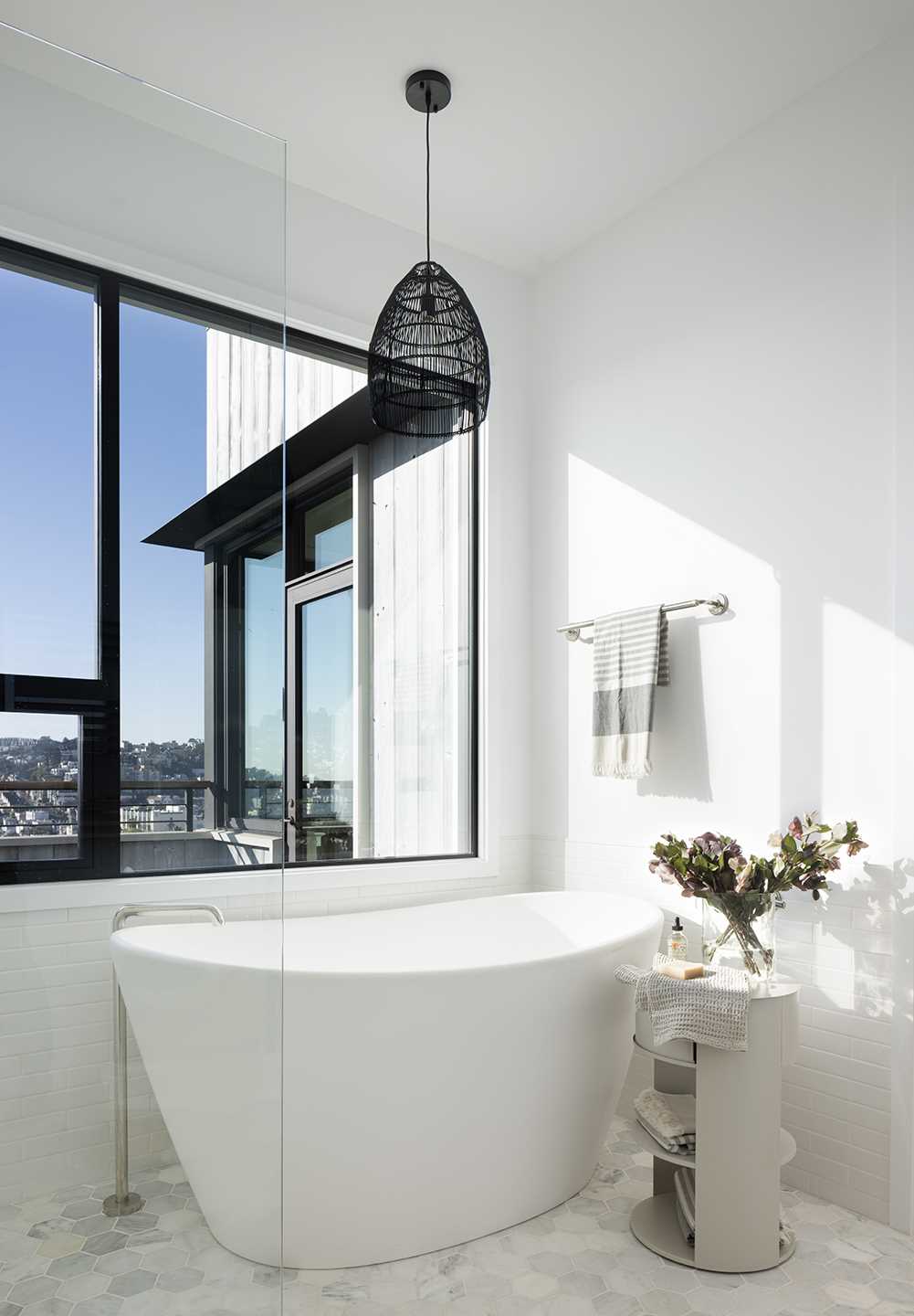 A modern bathroom with a freestanding bathtub positioned under the windows.