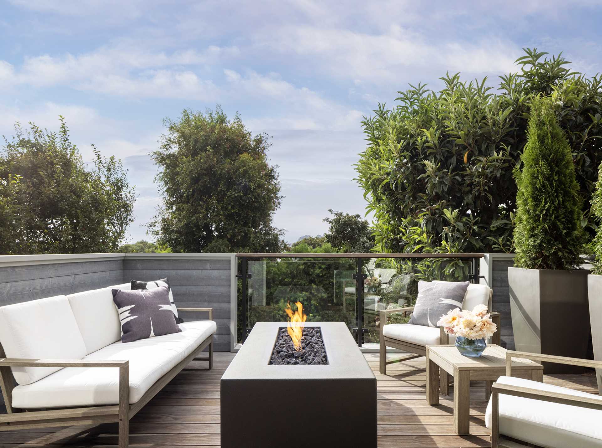 A modern deck with an outdoor fireplace and lounge seating.