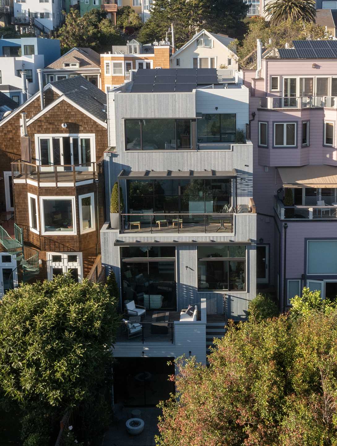 The rear of this renovated home shows the different layers, where living spaces were expanded and stepped volumes cascading down from the top floor were introduced, creating a seamless connection with the outdoors through a series of decks and balconies.