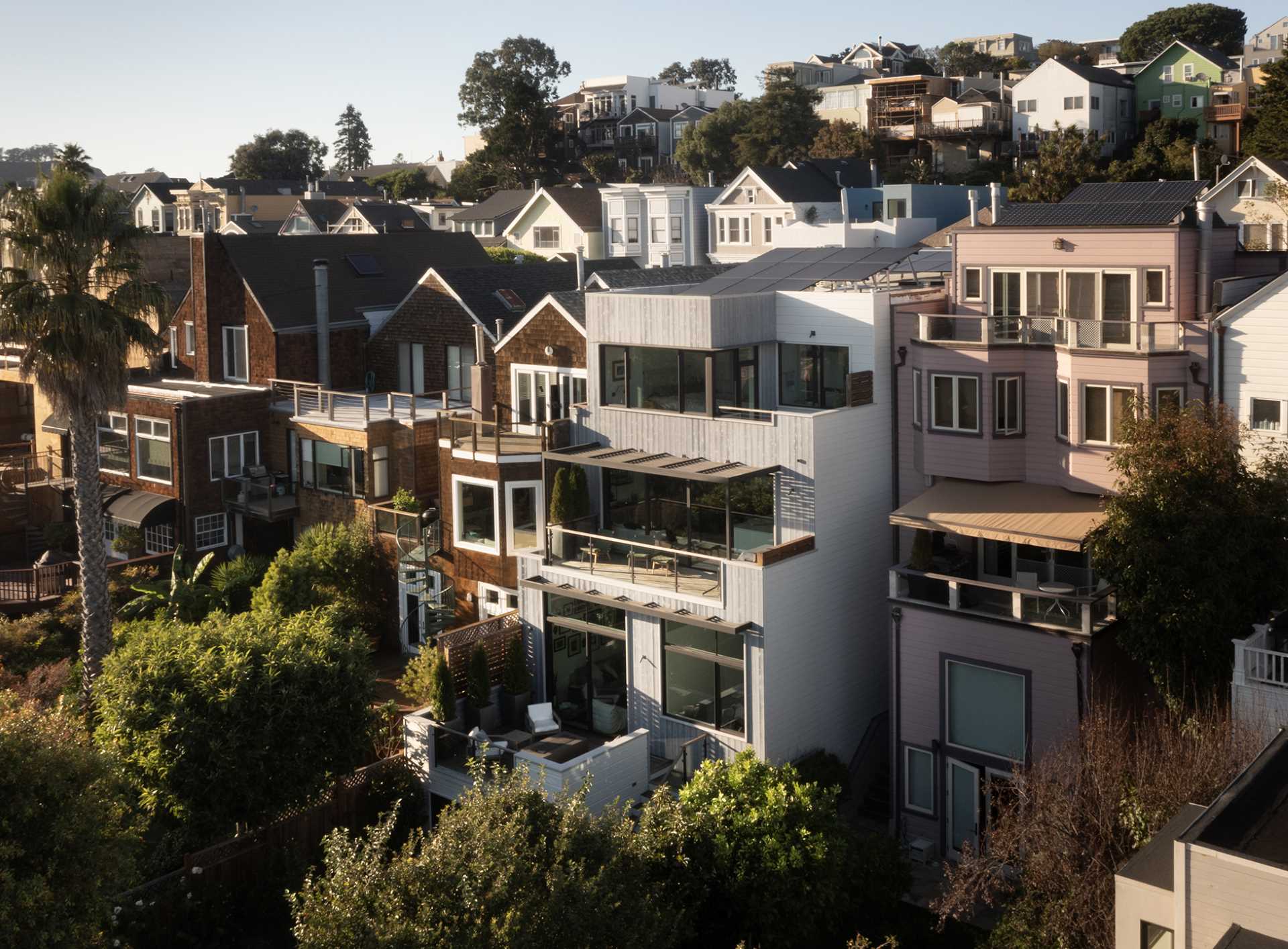 The rear of this renovated home shows the different layers, where living spaces were expanded and stepped volumes cascading down from the top floor were introduced, creating a seamless connection with the outdoors through a series of decks and balconies.