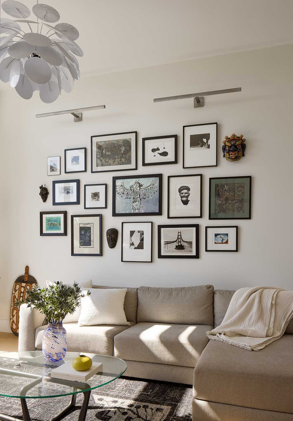 A modern living room with a wall of art highlighted by gallery lights.