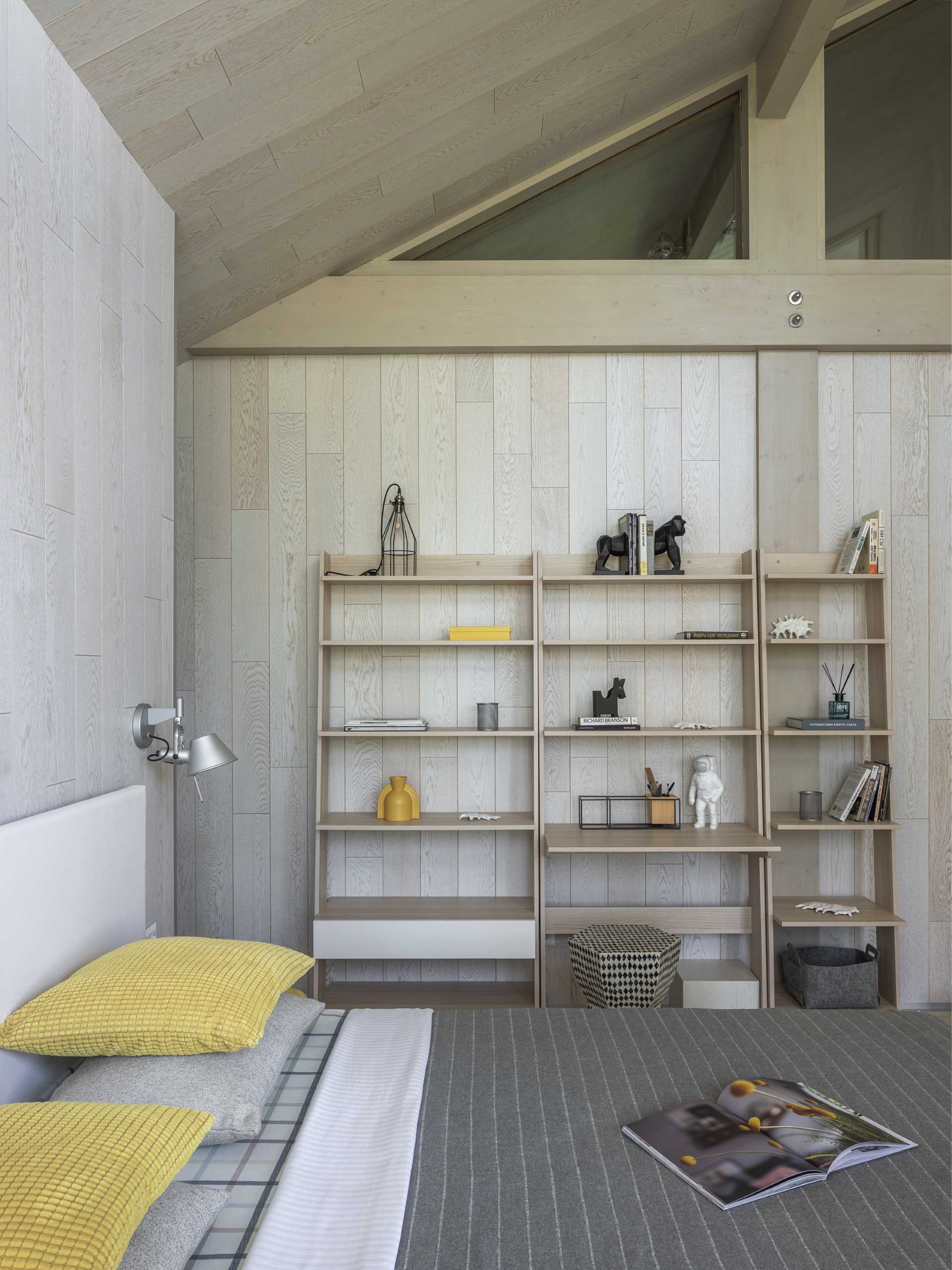 A contemporary bedroom with light wood walls and a white bed frame.