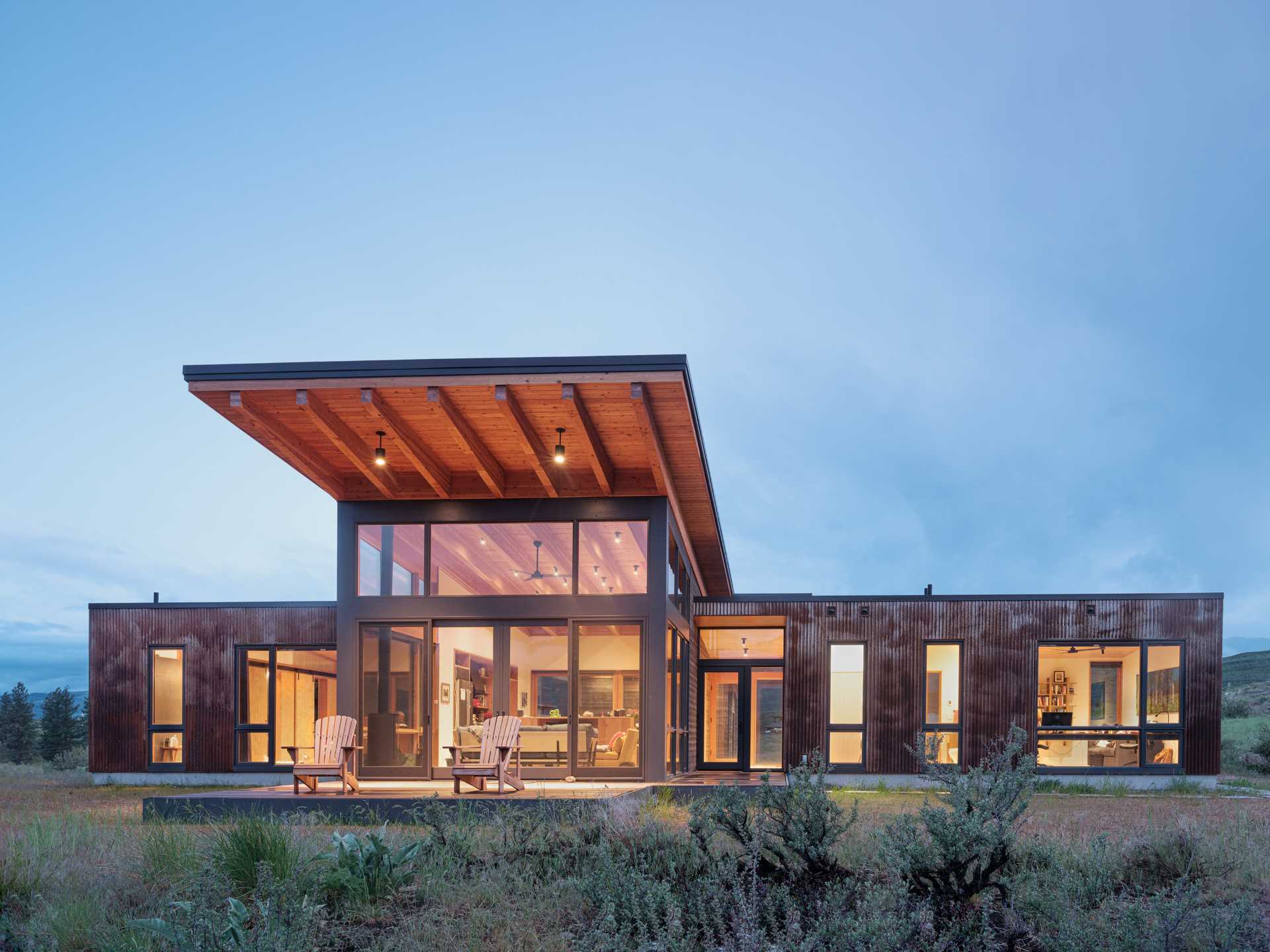 This modern home is clad in a combination of distressed wood siding, dark bronze composite, and pre-weathered corrugated steel.