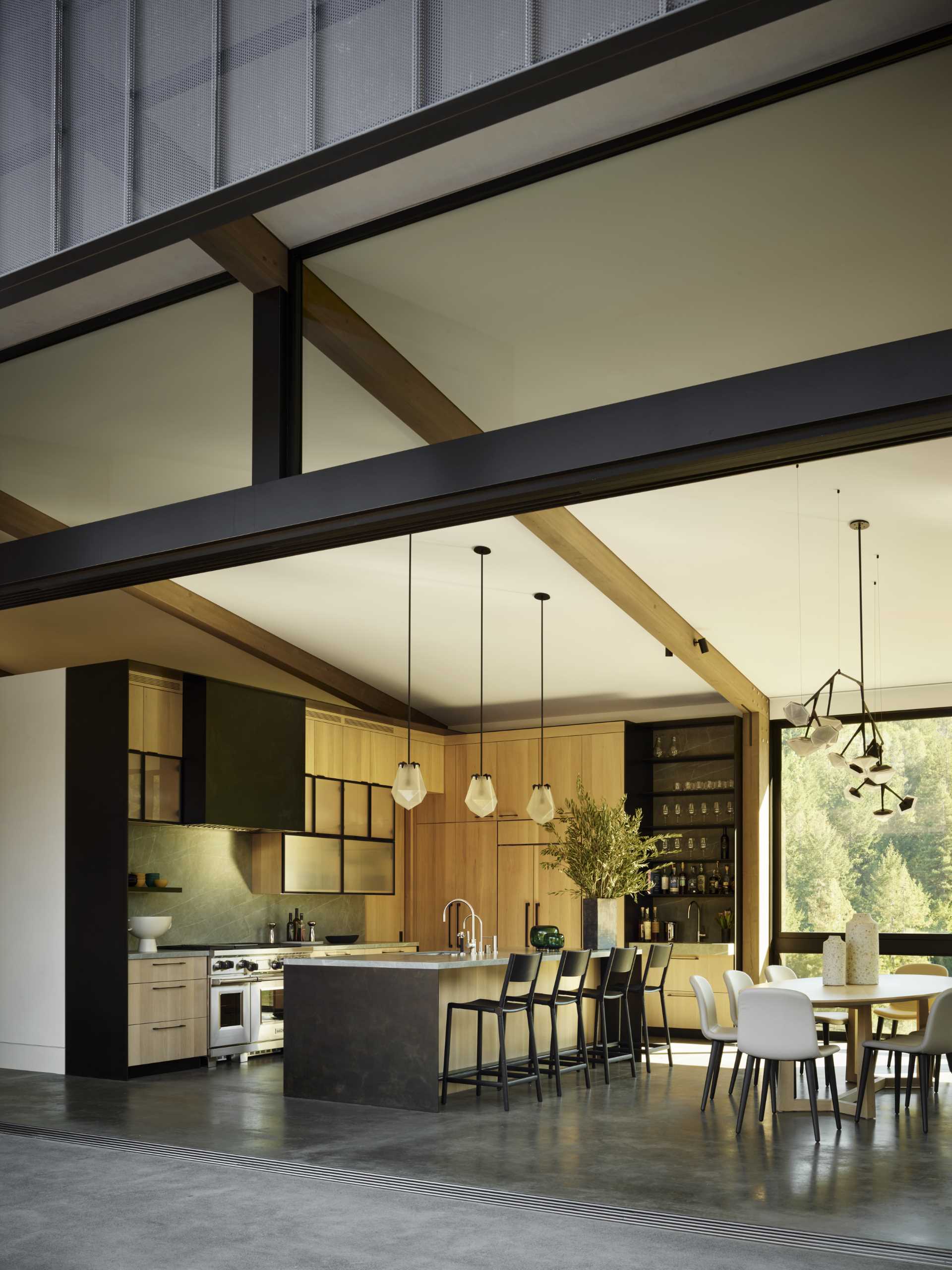 Inside this modern home, there's a great room with a living area, dining area, and kitchen, which also features features a pitched ceiling and exposed wood beams.