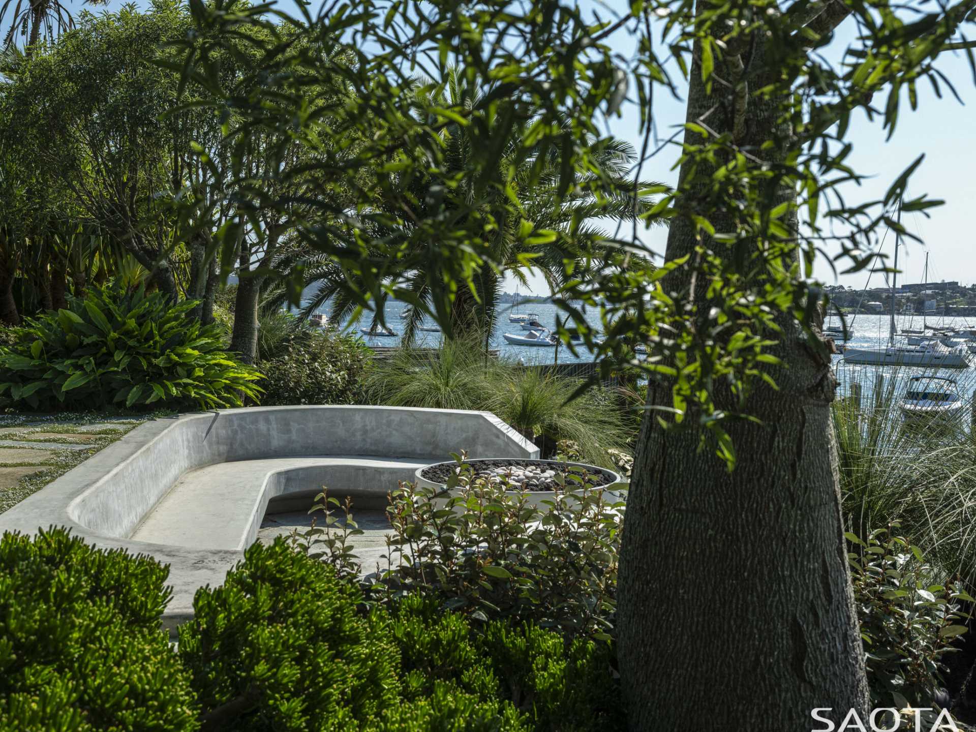 A path leads down to a built-in seating area by the water's edge.