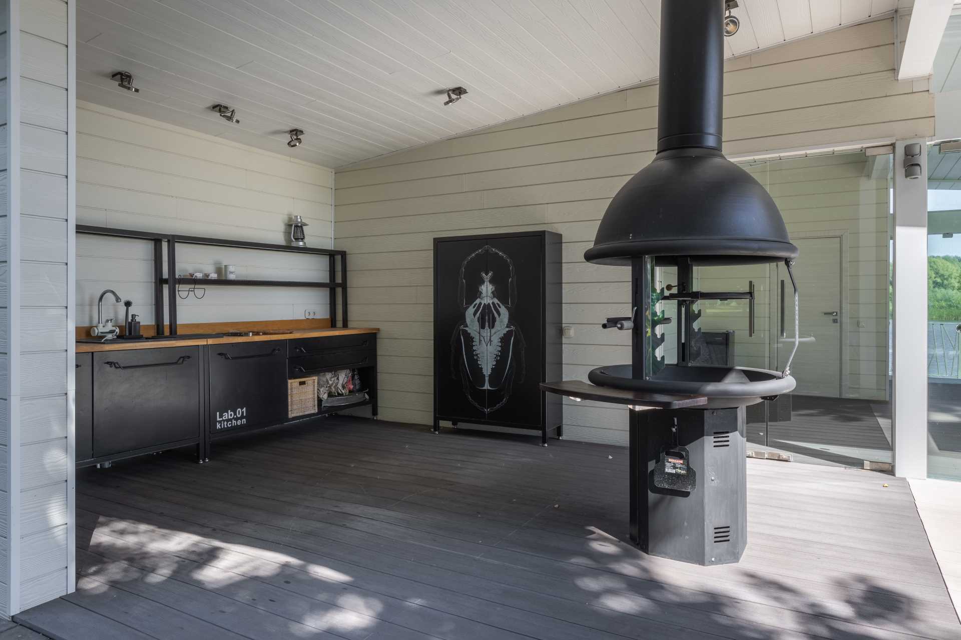 An outdoor pavilion that includes a kitchen with bbq, a covered dining area, and a lounge area.