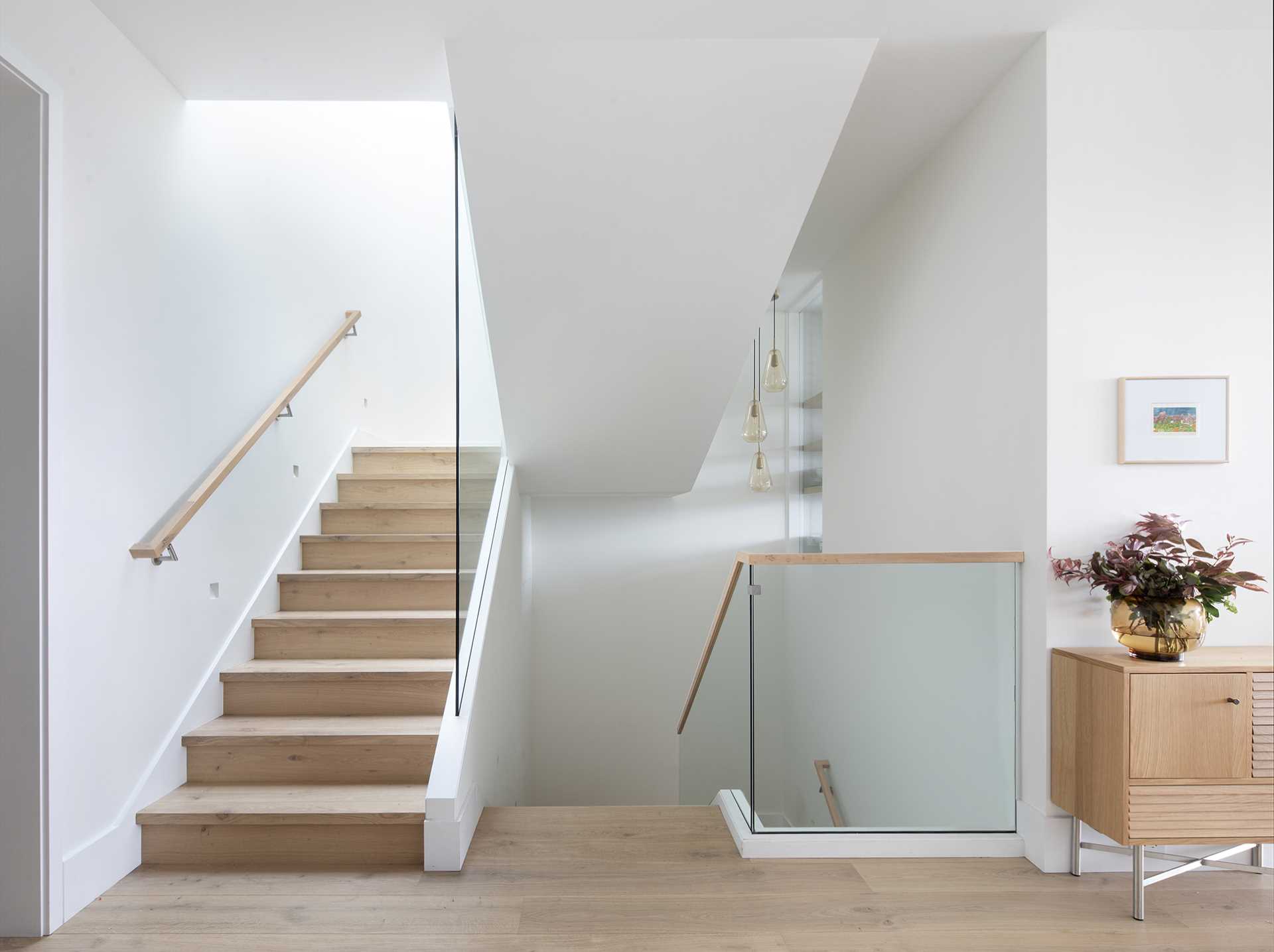 The stairwell connects all of the different levels of the home and features wood treads, while the glass railings allow natural light to travel throughout the space.