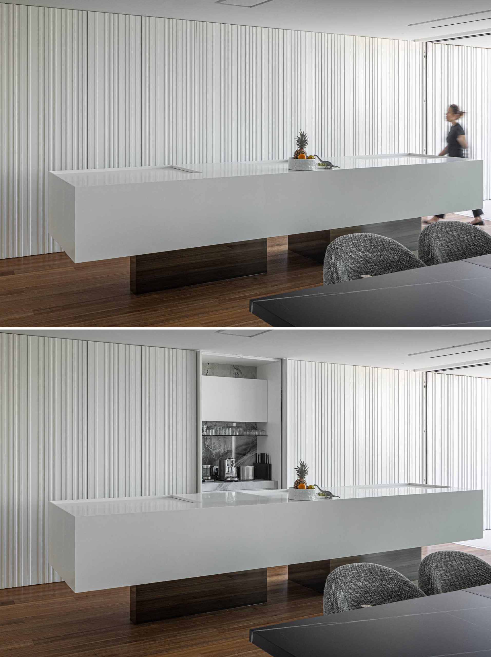 In this modern white kitchen, the textured wall hides the kitchen cabinets, while a sculptural light adds an artistic moment.